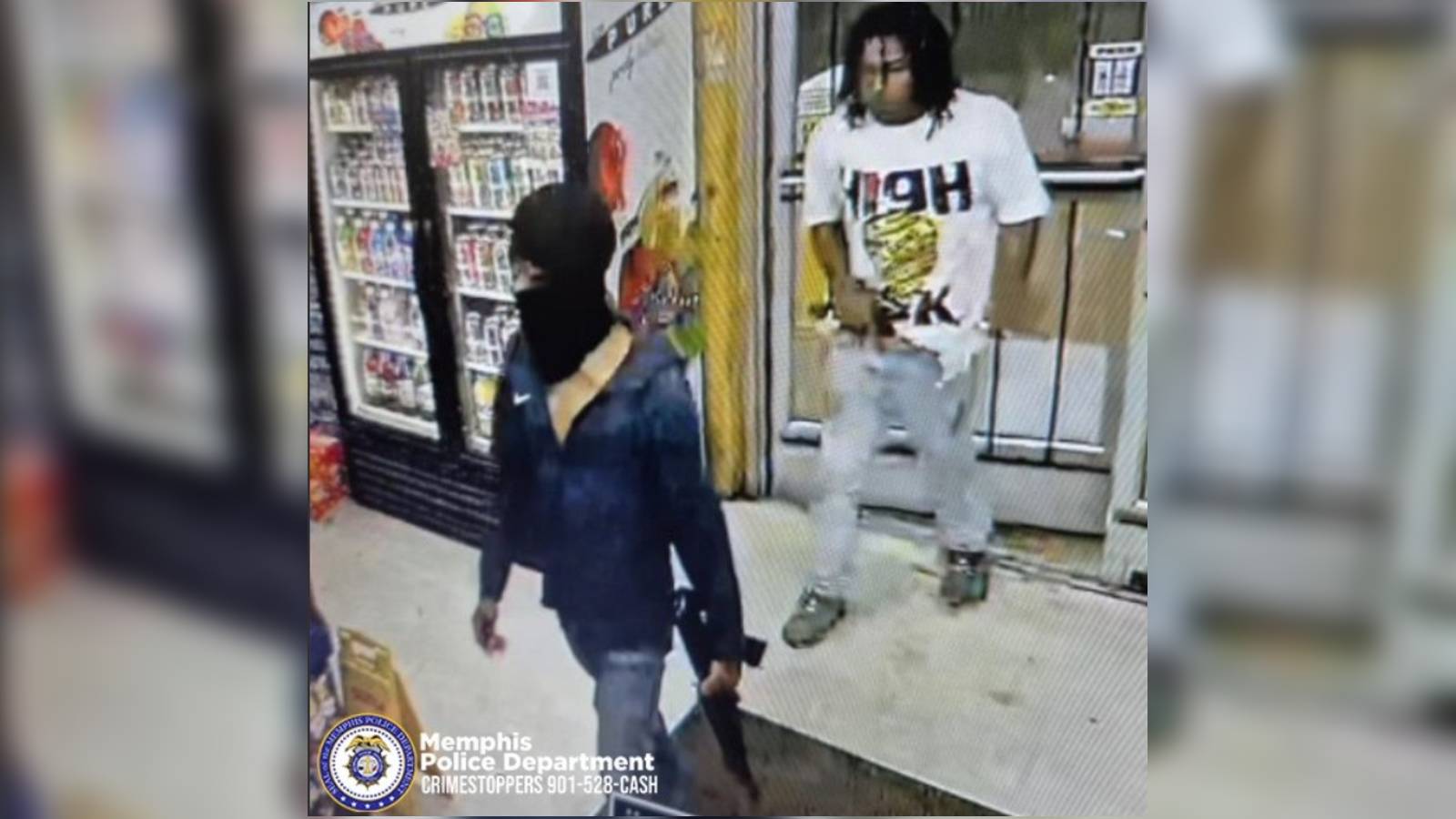 surveillance footage showing one masked man carrying a rifle and another with a handgun in the waistband of his pants.