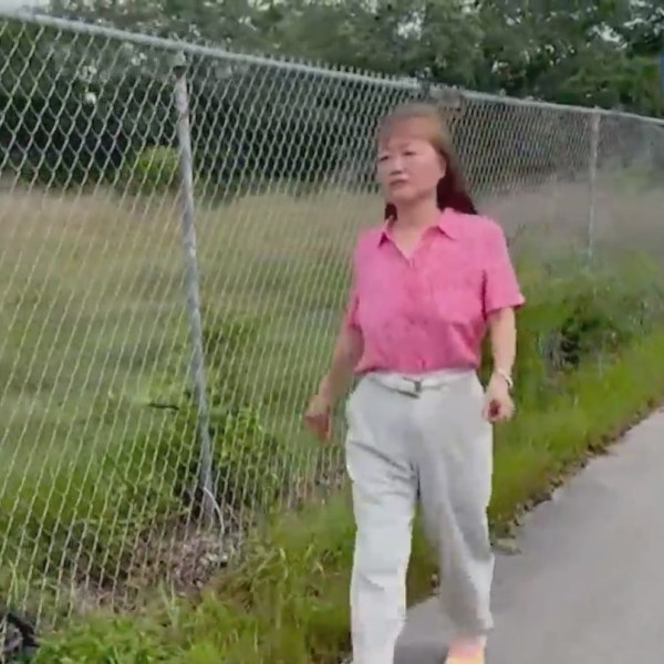 woman walking along a road near a fence