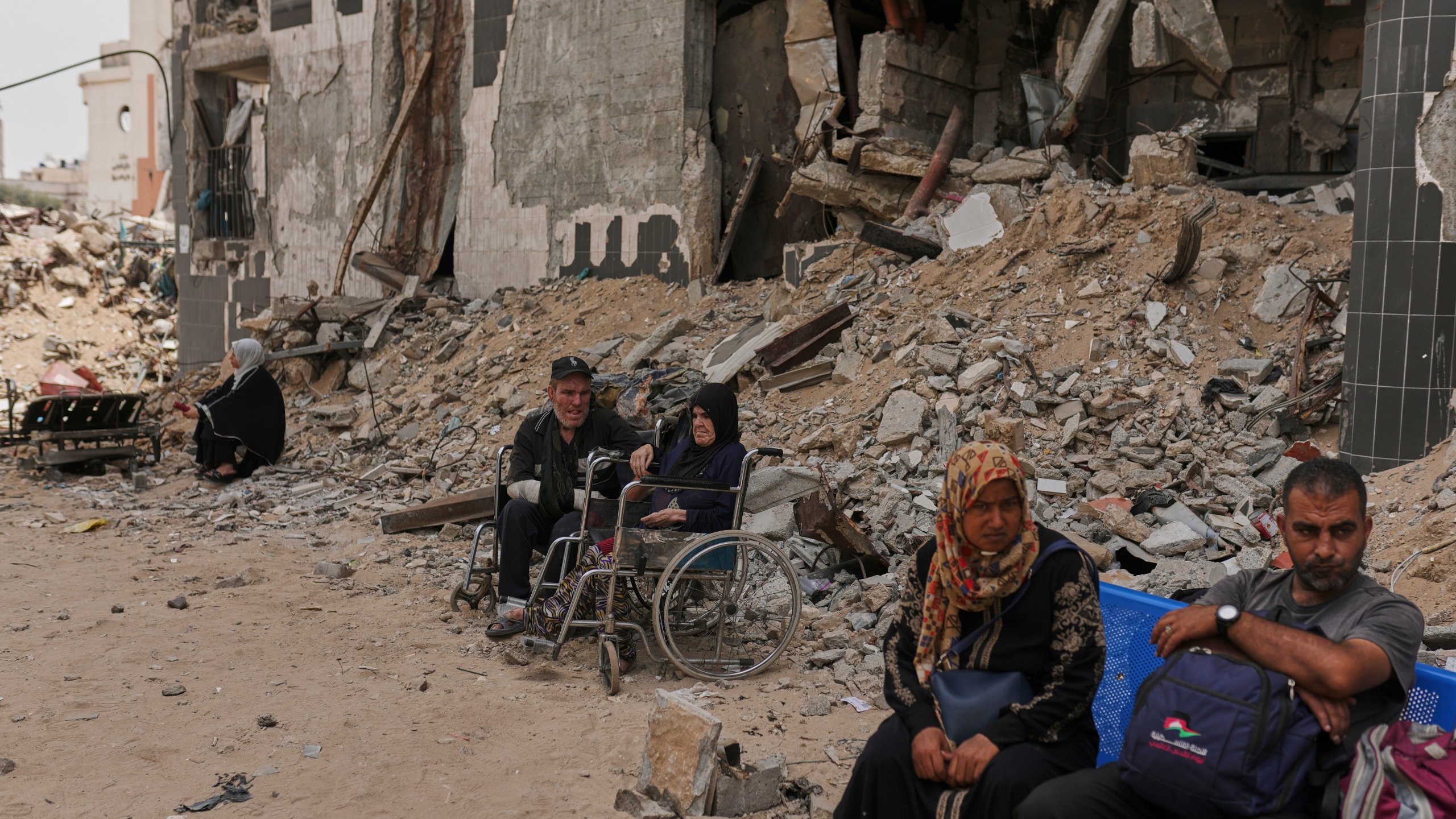 Kidney patients sit amid the destruction caused by the Israeli army at Shifa Hospital compound in Gaza City on Tuesday, July 1, 2025, as they wait to leave after the facility suspended its dialysis unit services due to fuel shortages needed to power its generators. (AP Photo/Jehad Alshrafi)