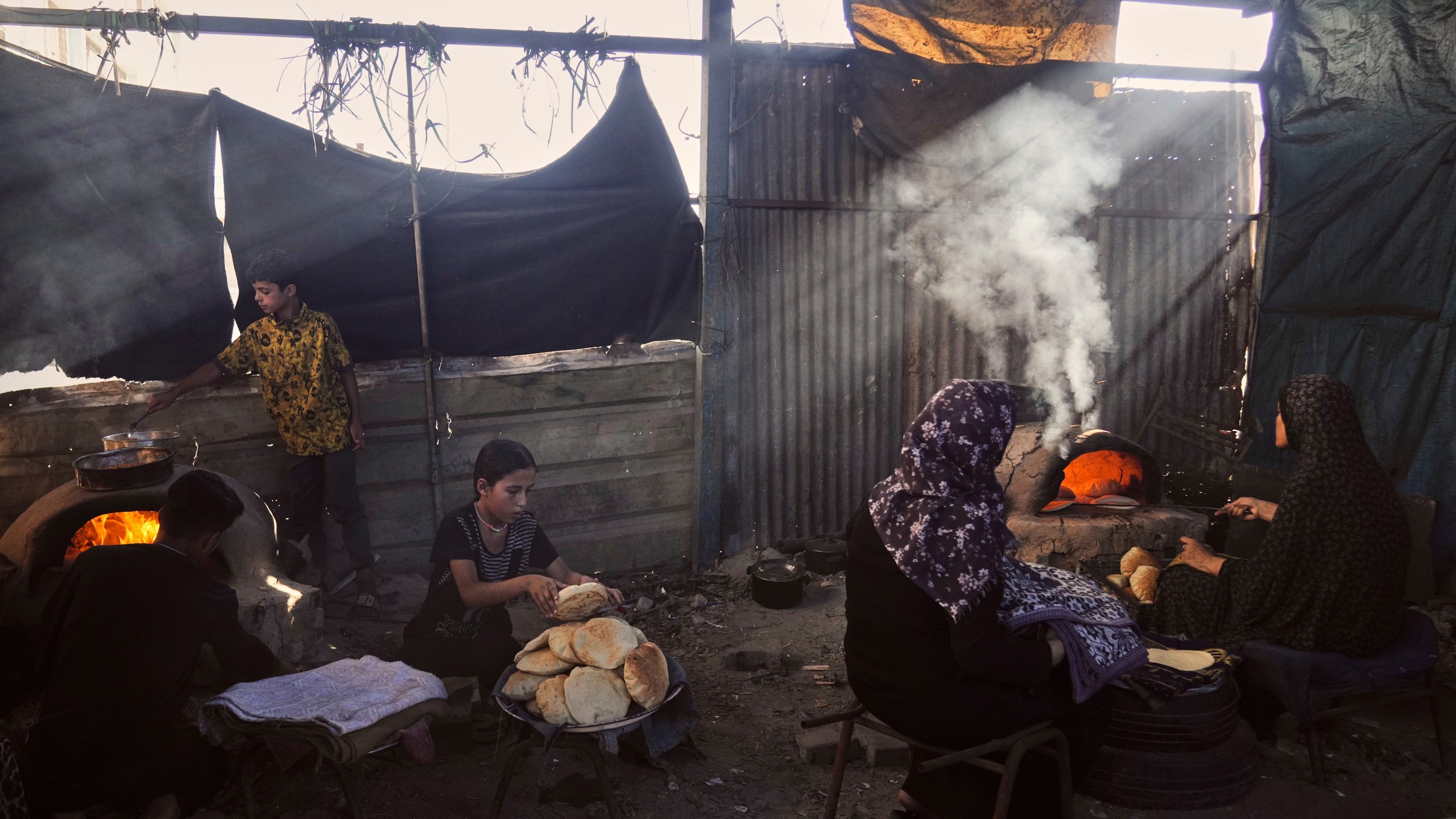 Displaced Palestinians bake bread in a school now serving as a shelter in Deir al-Balah, Gaza Strip Sunday, July 6, 2025. (AP Photo/Abdel Kareem Hana)
