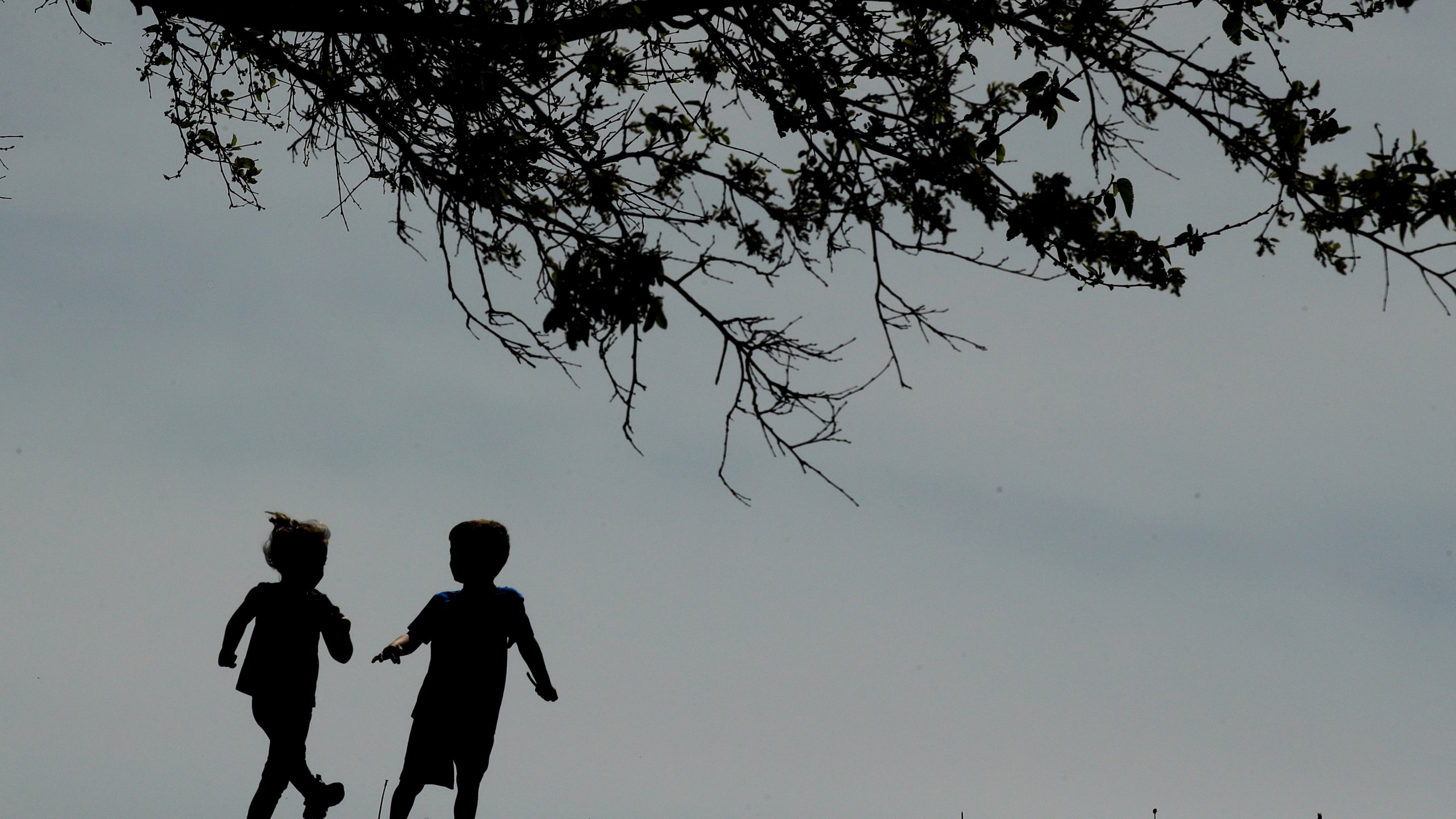 FILE - Children run on the lawn at the Liberty Memorial in Kansas City, Mo., on April 28, 2020. (AP Photo/Charlie Riedel, File)