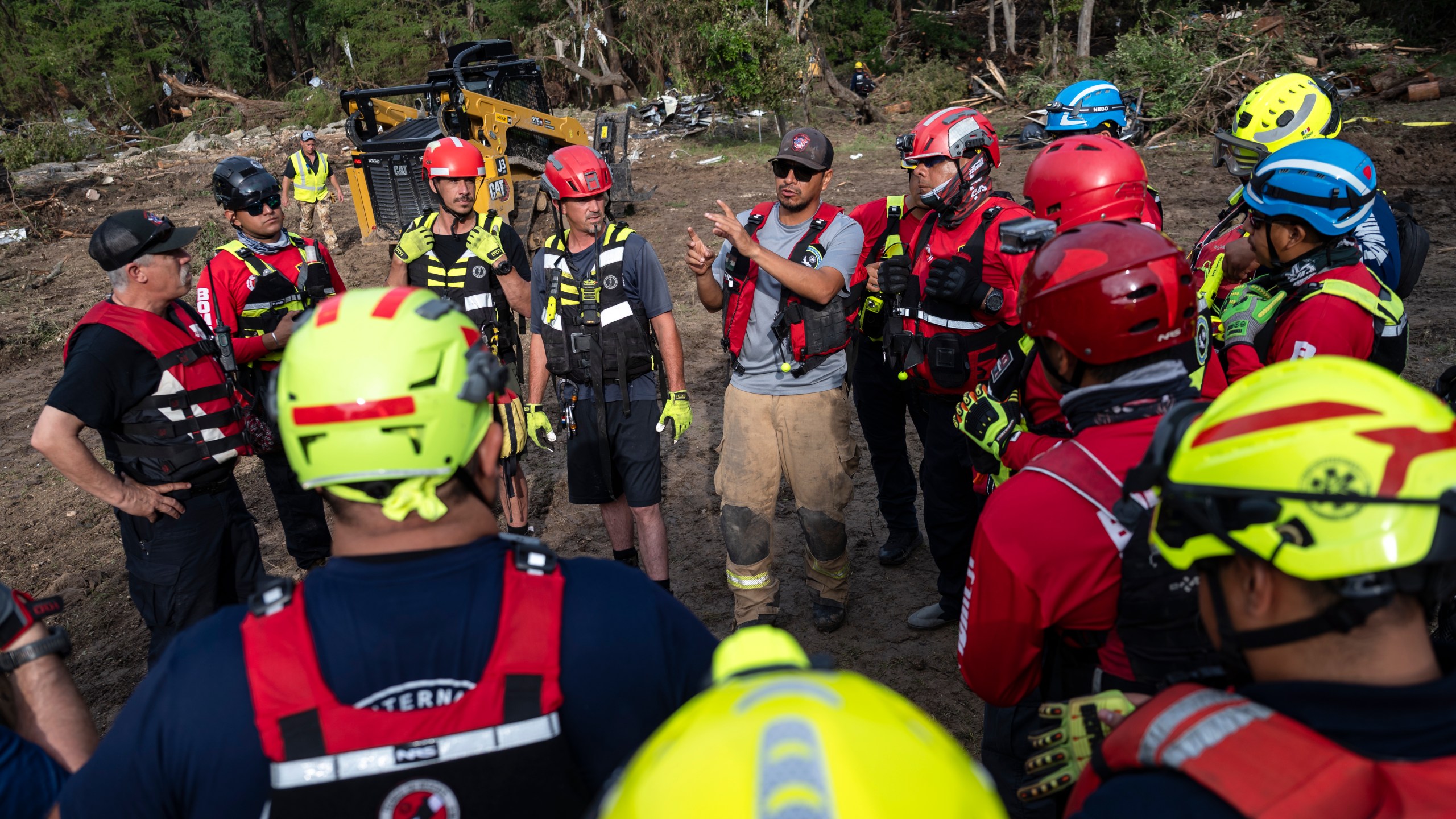 A crew of firefighters from Ciudad Acuna, Mexico, gather for a briefing as they aid in search and rescue efforts near the Guadalupe River after a flash flood swept through the area Monday, July 7, 2025, in Ingram, Texas. (AP Photo/Eli Hartman)