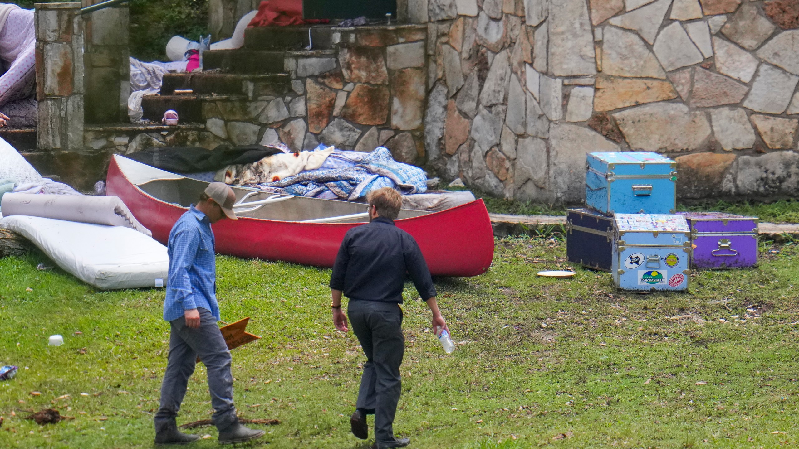 A person carries a sign reading "Do Good. Do No Harm. Keep Falling In Love with Jesus" after it was salvaged from debris washed up near Camp Mystic along the Guadalupe River after a flash flood on Friday swept through the area, Sunday, July 6, 2025, in Hunt, Texas. (AP Photo/Julio Cortez)