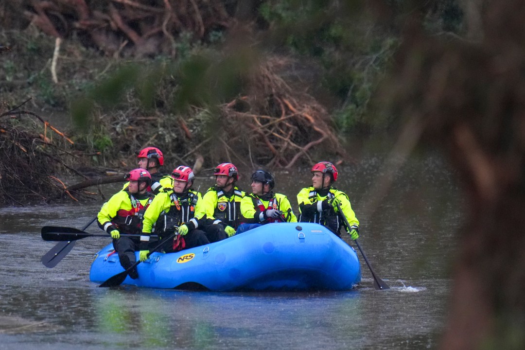 Officials ride a boat as they arrive to assist with a recovery effort at Camp Mystic along the Guadalupe River, Sunday, July 6, 2025, in Hunt, Texas, after a flash flood swept through the area. (AP Photo/Julio Cortez)