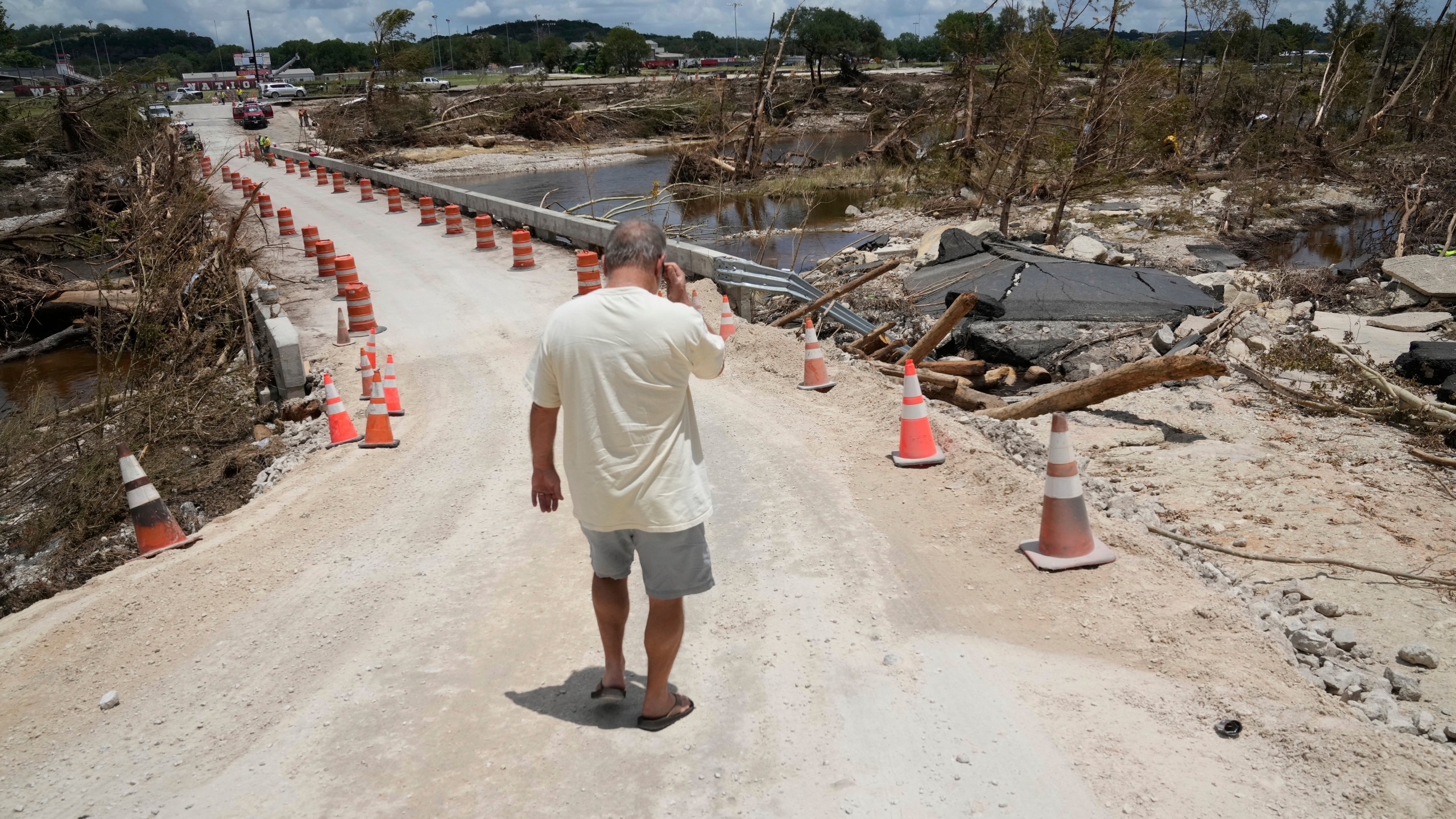 Resident Paul Snyder walks down the road to check out the condition of the bridge along the Guadalupe River after flooding in Ingram, Texas on Wednesday , July 9, 2025. (AP Photo/Gerald Herbert)