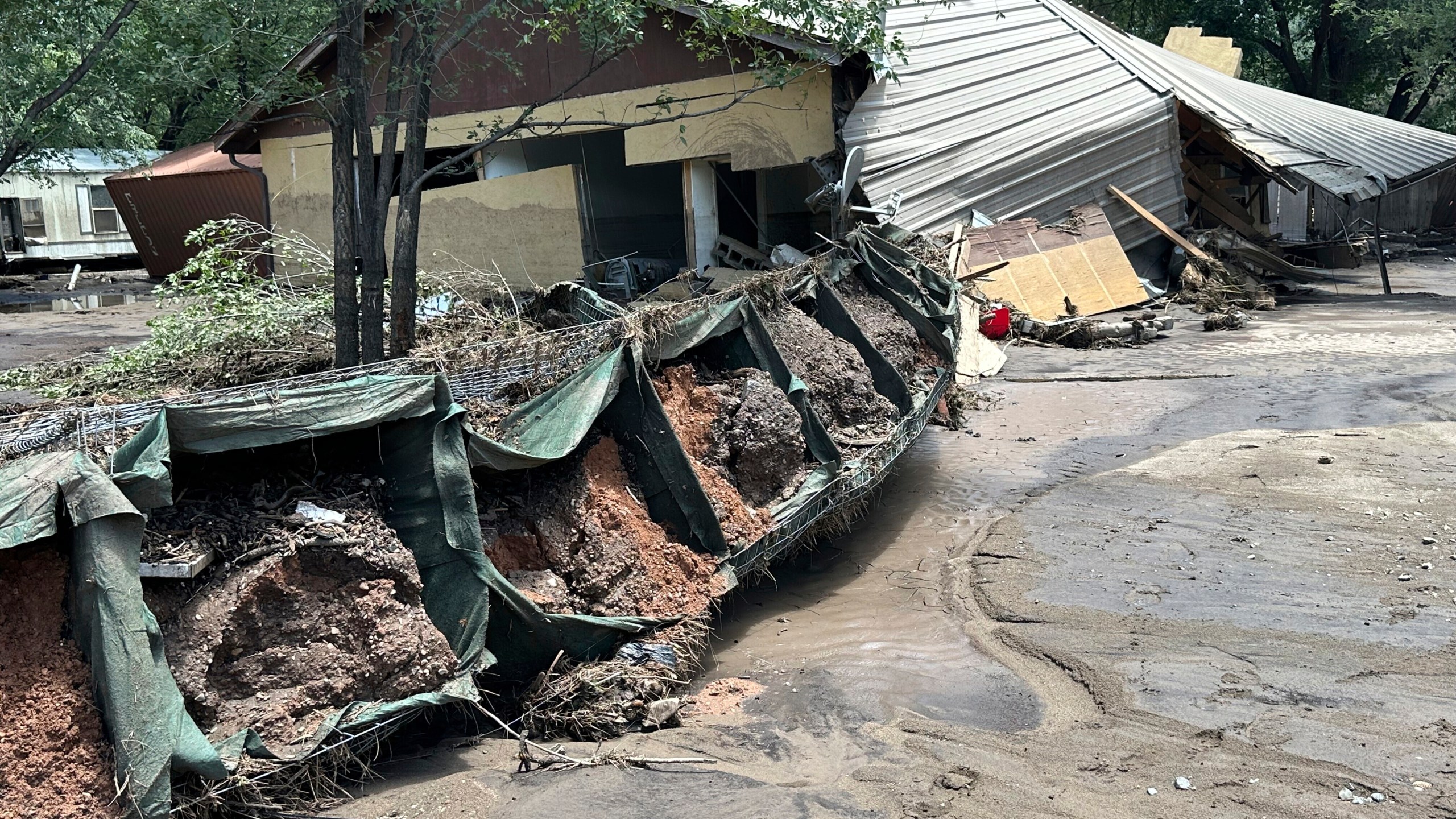 damage with mud and debris is swept to the side of a road