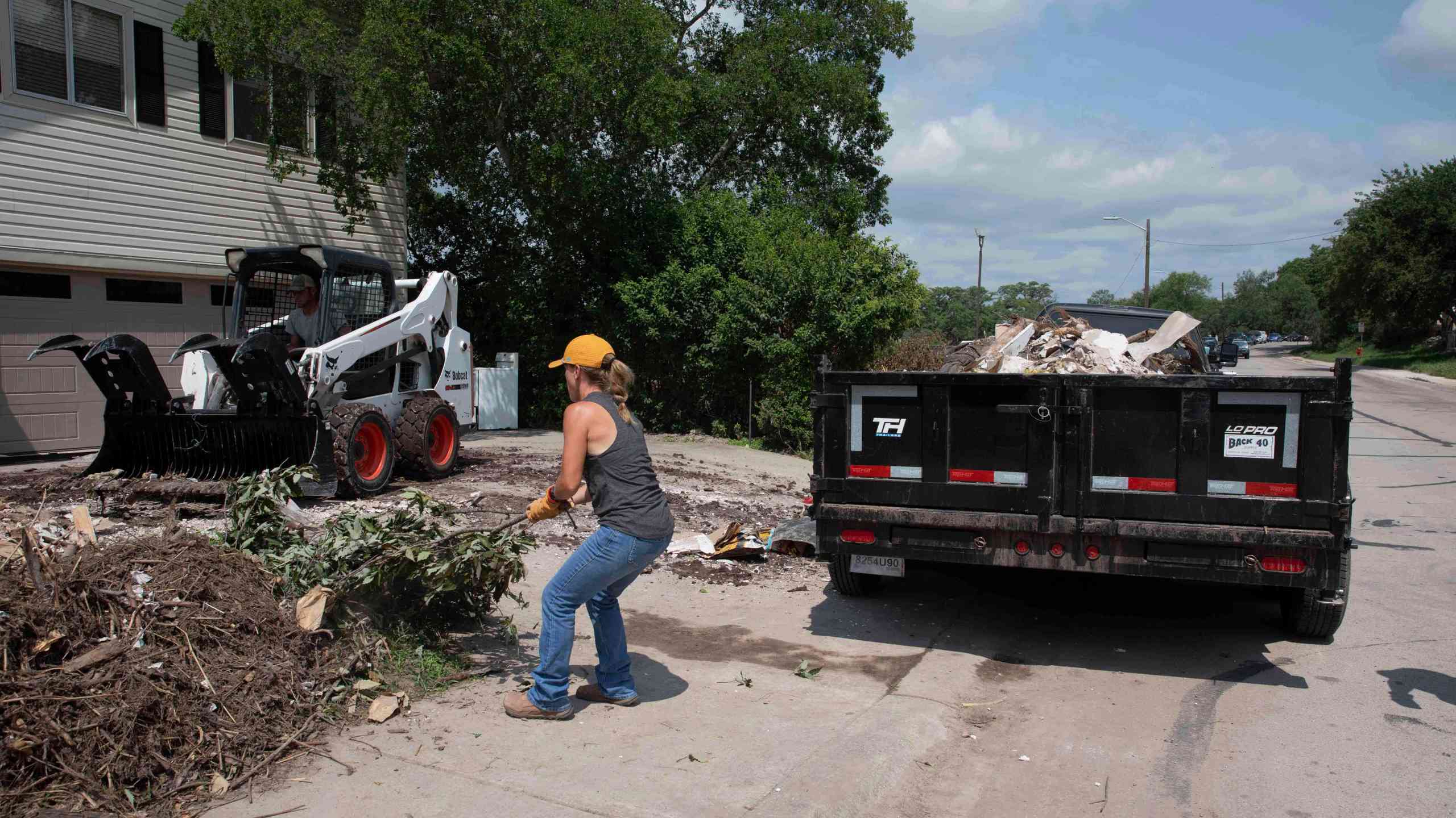 A volunteer removes tree debris from a flood-damaged home on Guadalupe Street in Kerrville, Texas, on July 12, 2025. (AP Photo/Gabriela Aoun Angueira)