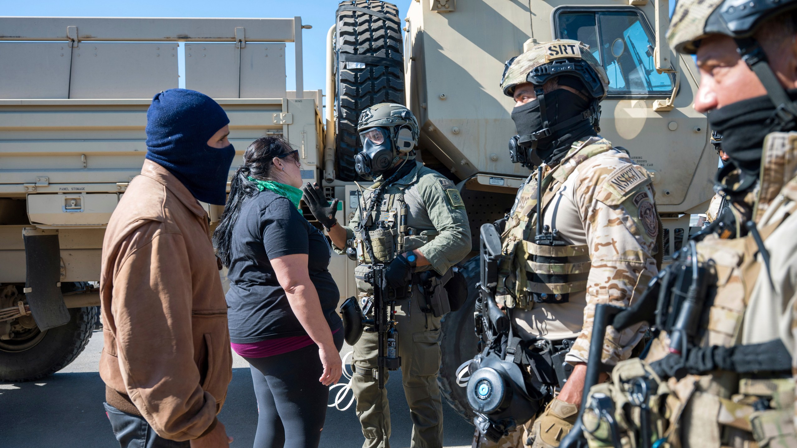 Federal immigration agents talk to Rebecca Torres, second left, after she tried to block a military vehicle during a raid in the agriculture area of Camarillo, Calif., Thursday, July 10, 2025. (AP Photo/Michael Owen Baker)
