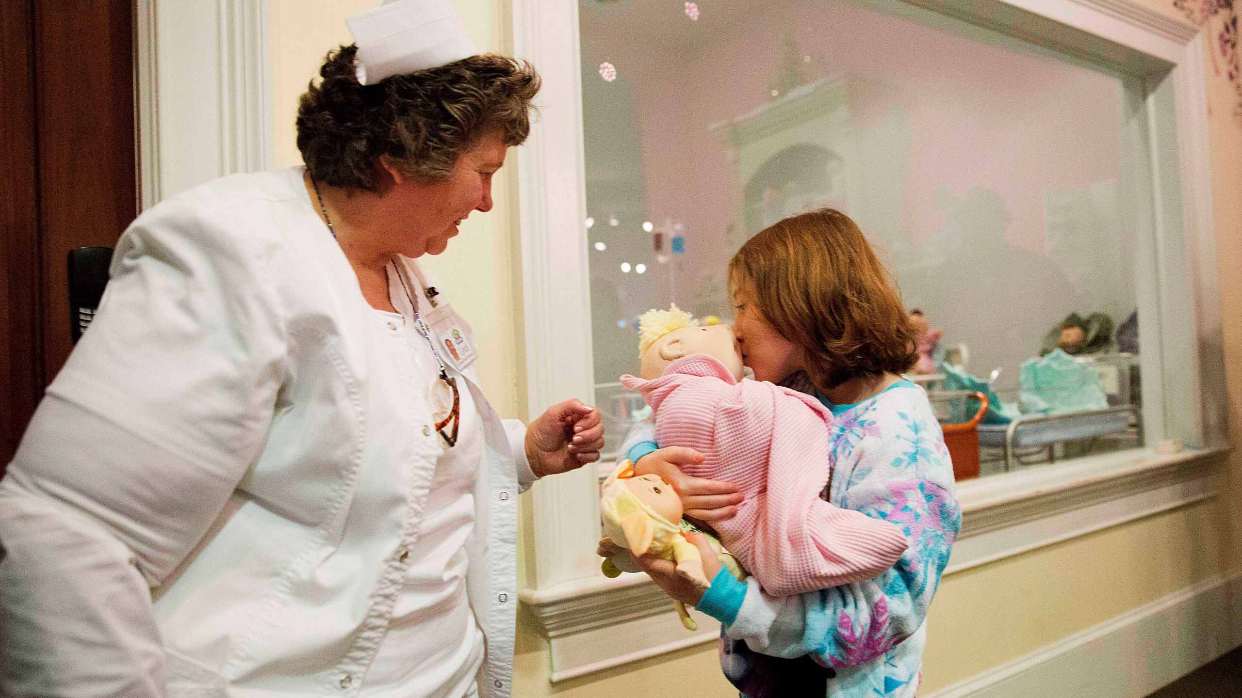 FILE - Talon Shaffer, right, kisses a Cabbage Patch Kid after it was delivered by Cyndi Pappadouplos, a "licensed patch nurse" at Babyland General Hospital, the birthplace of Cabbage Patch Kids, in Cleveland, Ga., on Nov. 21, 2014. (AP Photo/David Goldman, File)
