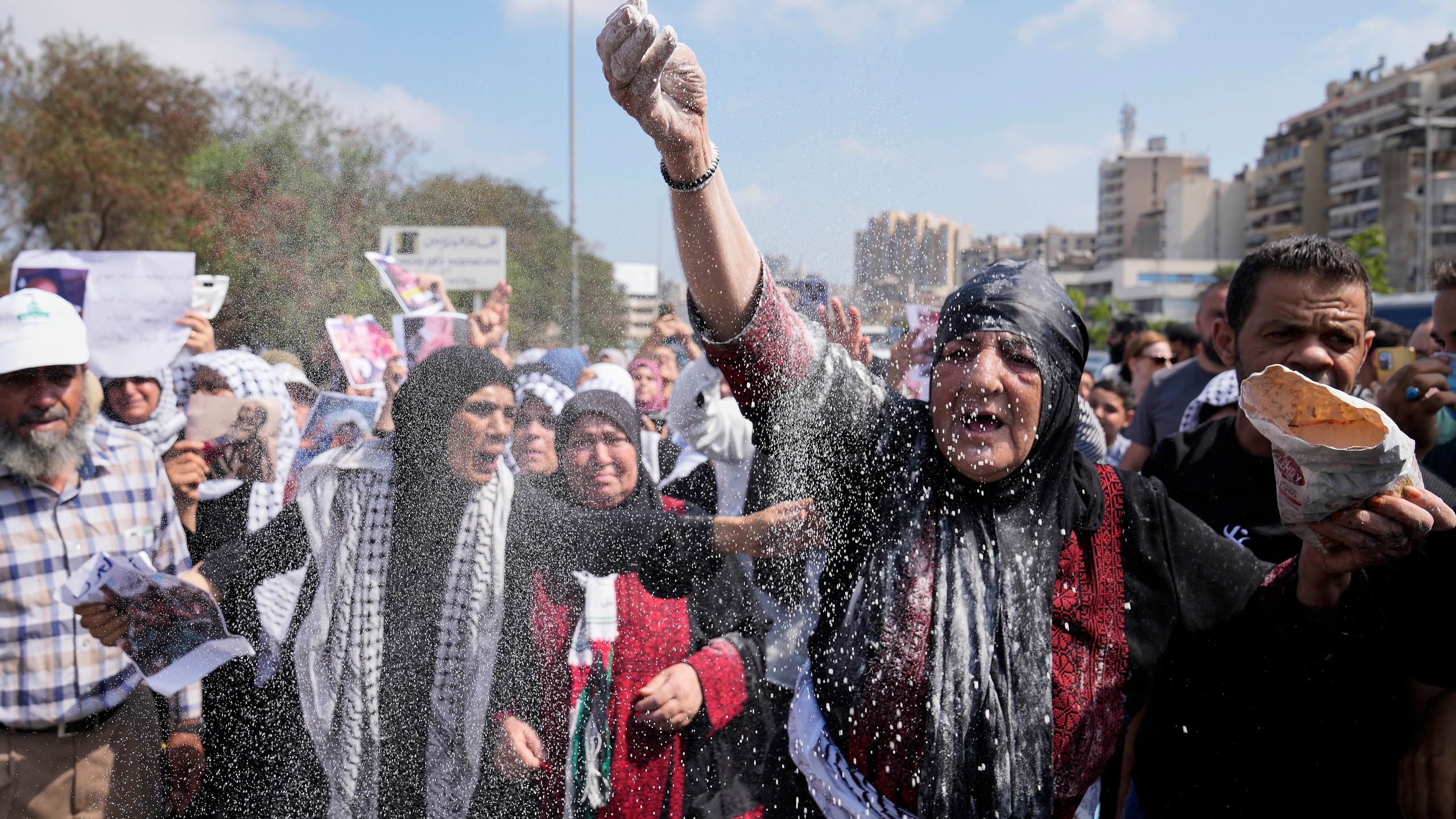 A woman throws flour, as she protests outside the Egyptian Embassy in Beirut, Lebanon, Wednesday, July 23, 2025, during a demonstration against the Israeli war and what they say starvation of civilians in the Gaza Strip. (AP Photo/Hussein Malla)