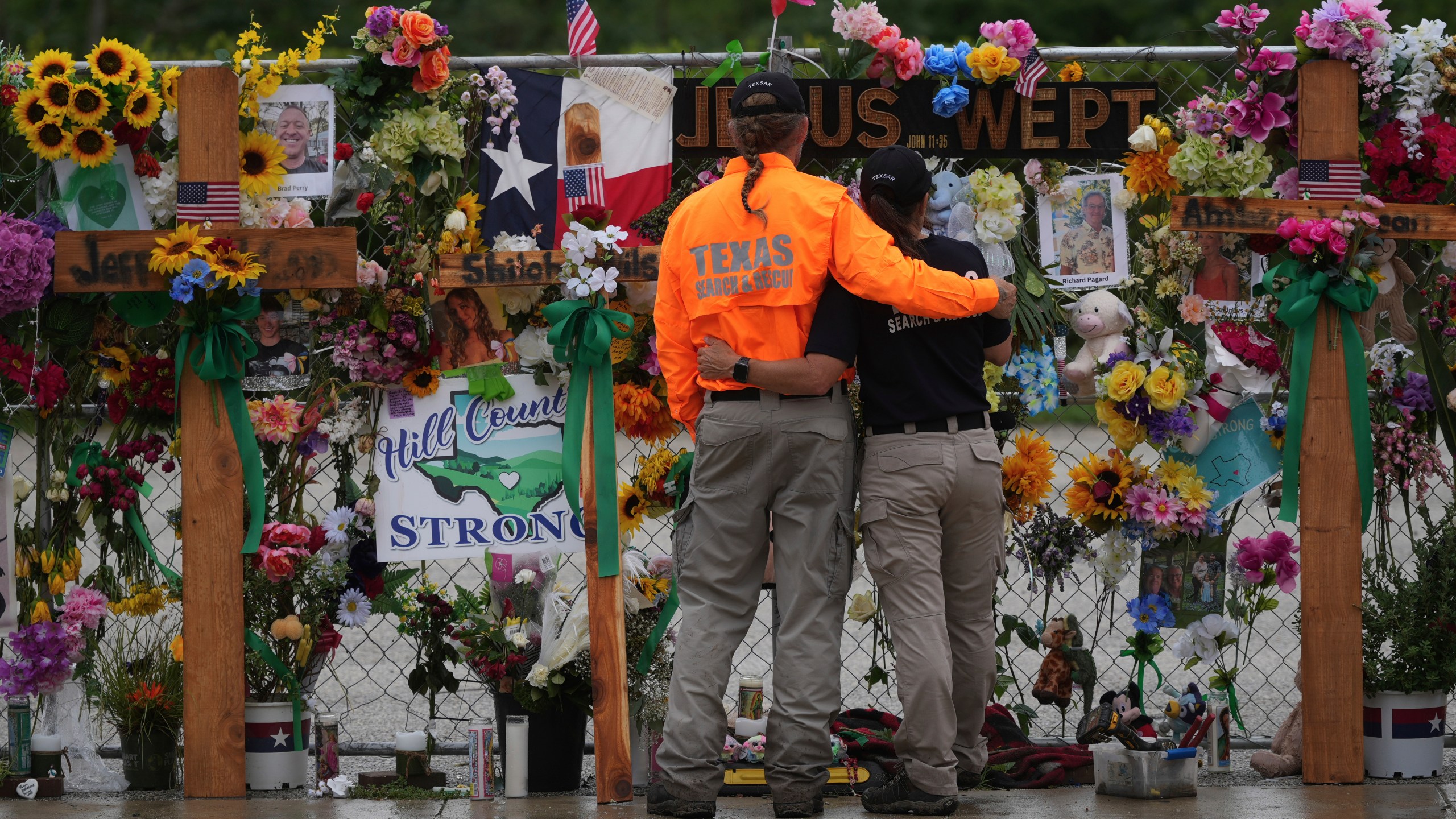 People embrace as they visit a memorial wall