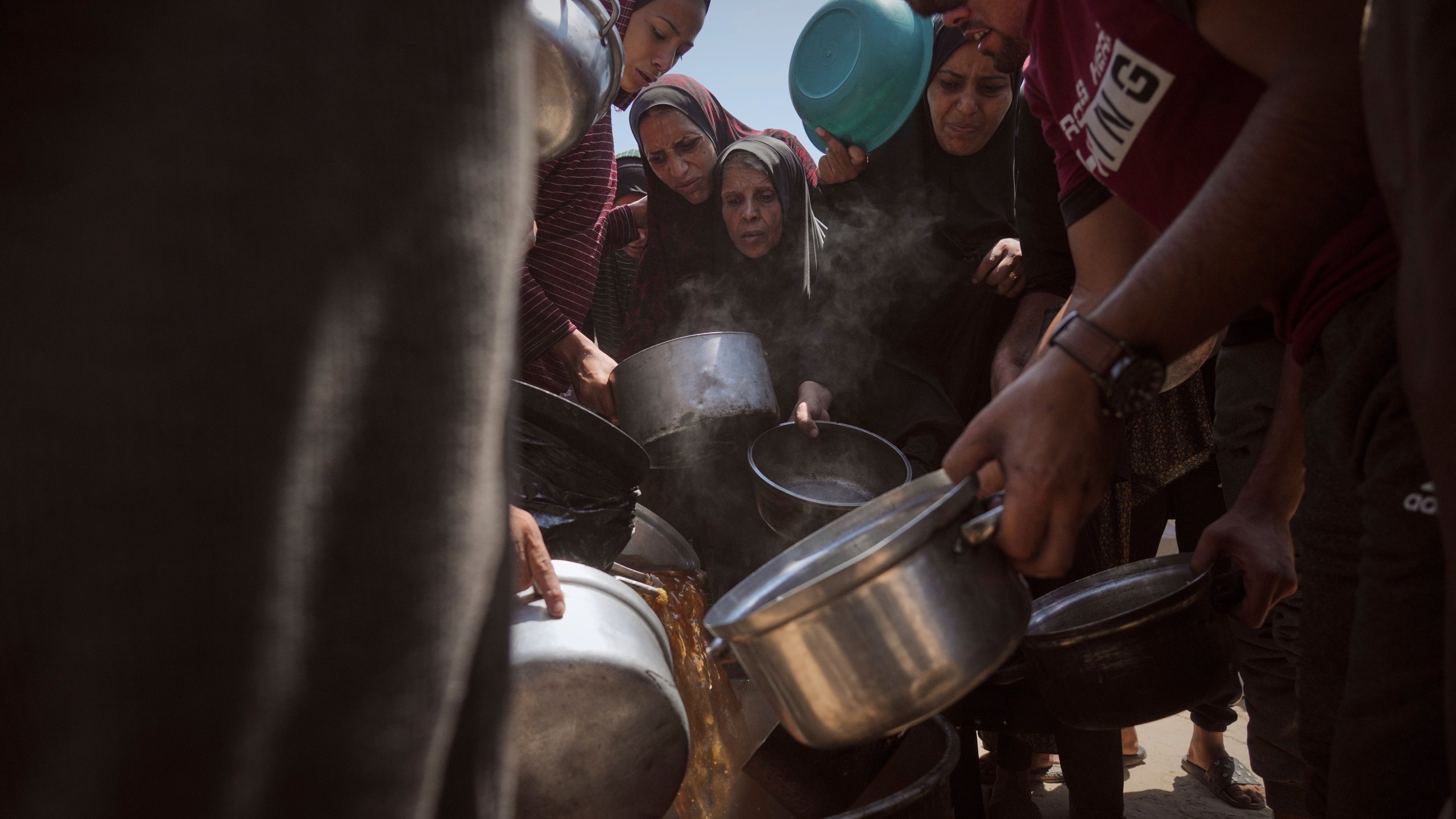 people crowd at an aid site in search of food