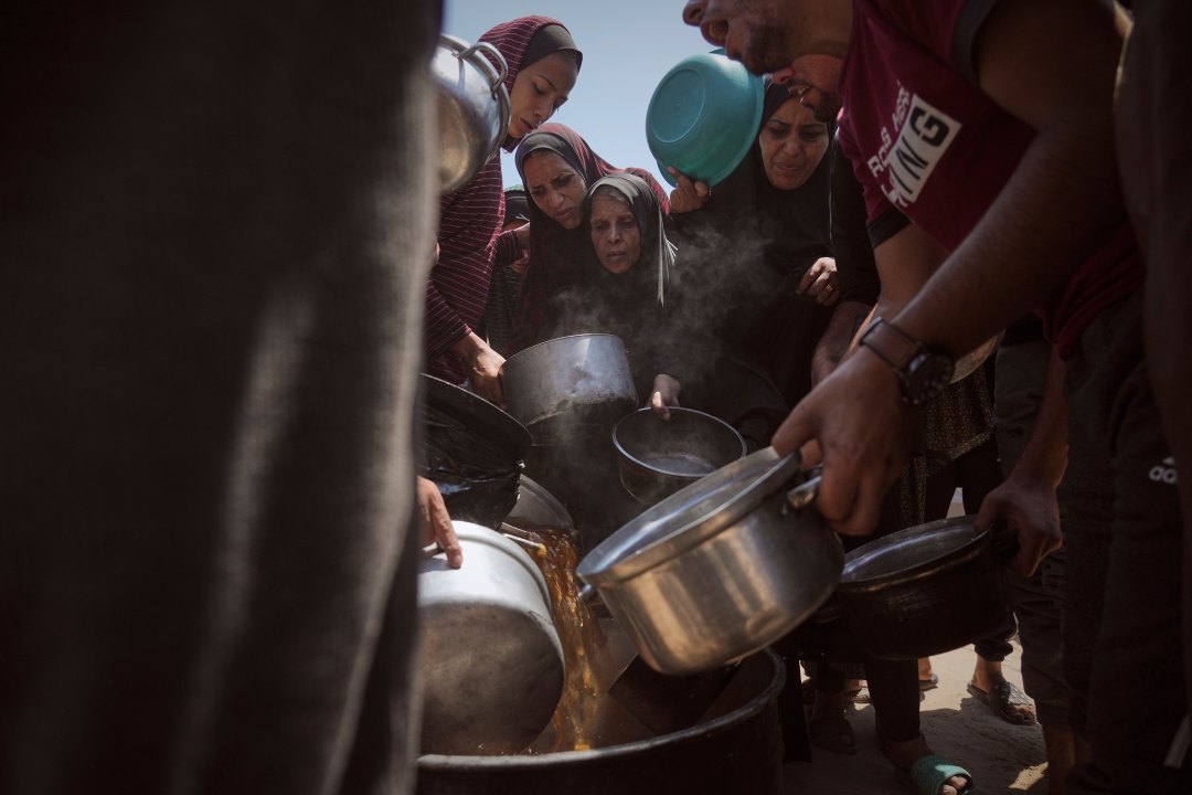 people crowd at an aid site in search of food