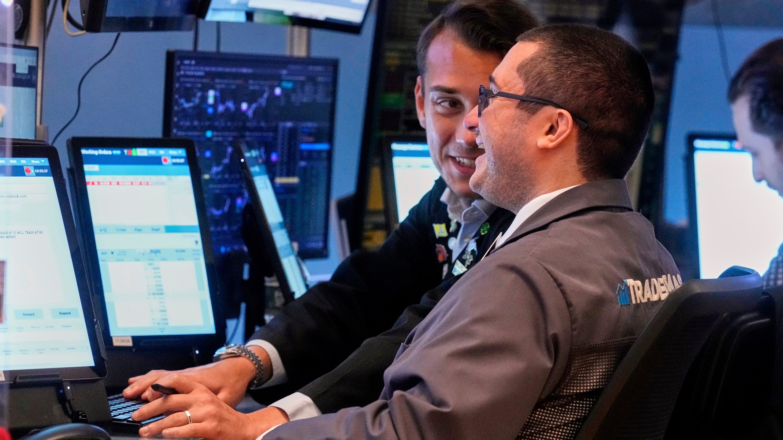 two men work on the floor of the stock exchange