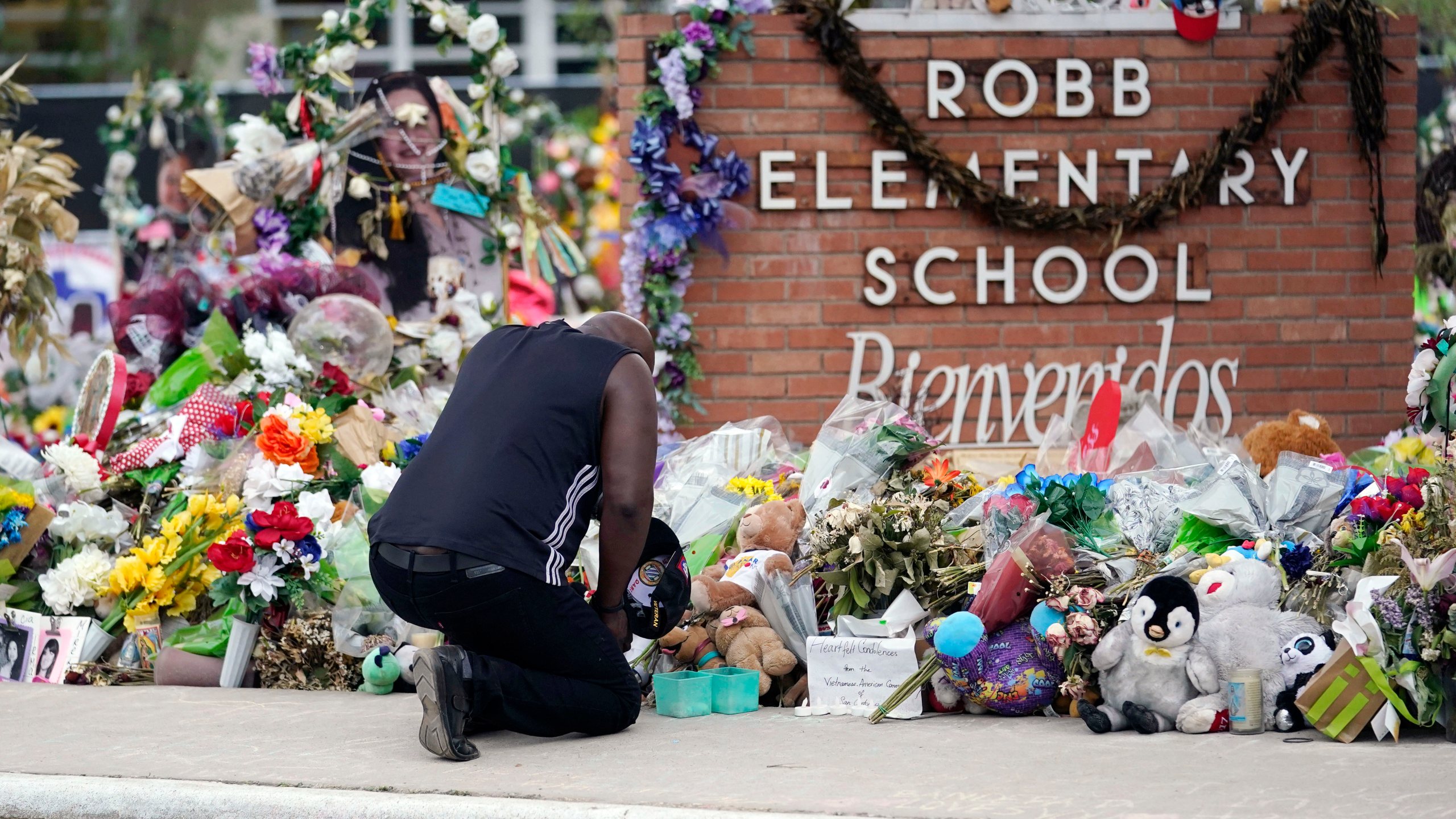 Man kneels before memorial at Robb Elementary School