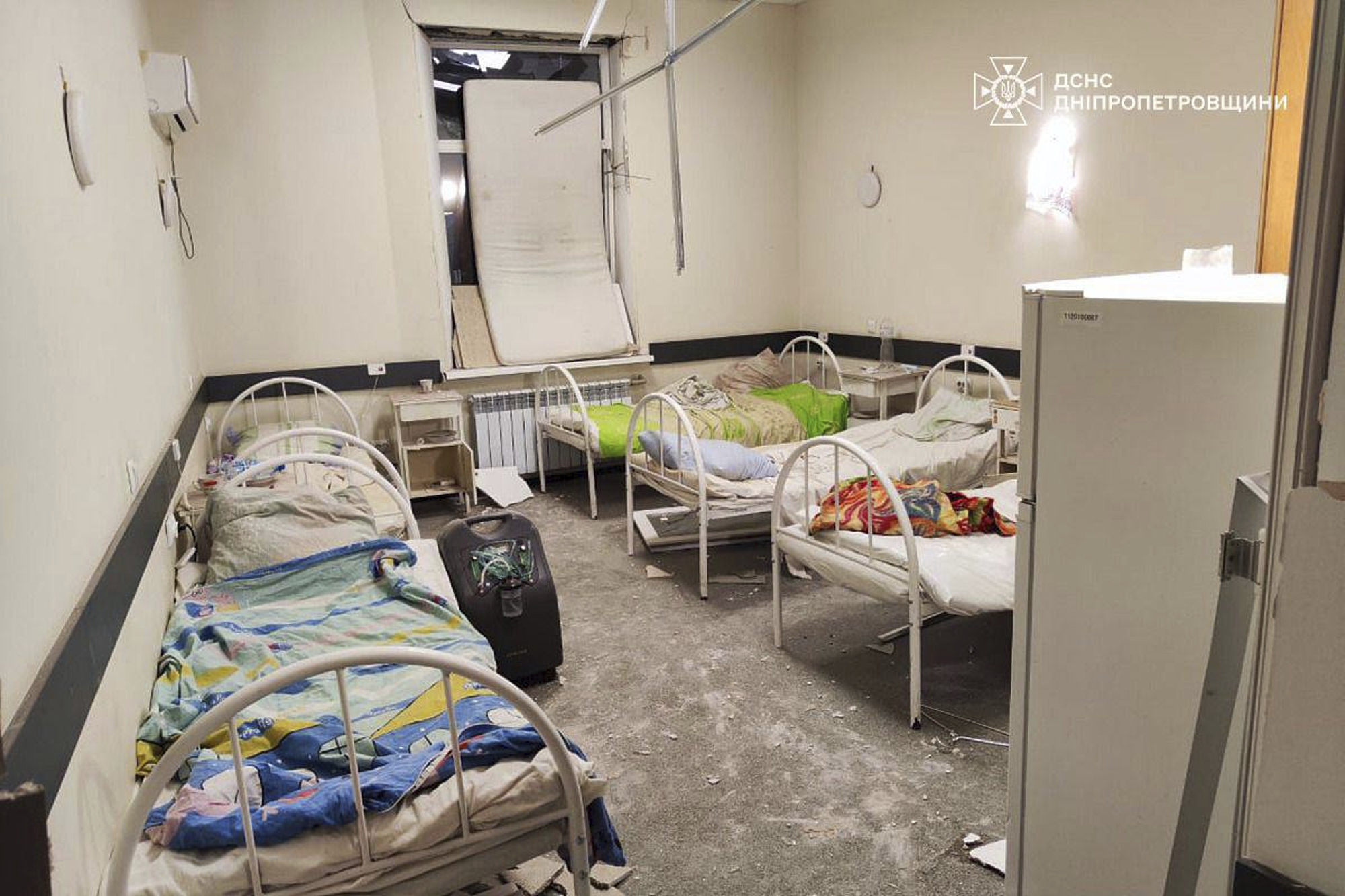 an empty hospital room with beds and debris from bombing