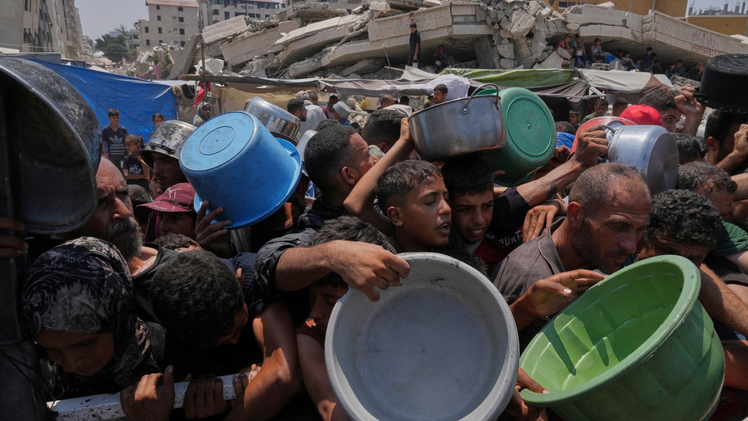 Palestinians struggle to get donated food at a community kitchen, in Gaza City, northern Gaza Strip, Saturday, July 26, 2025. (AP Photo/Abdel Kareem Hana)