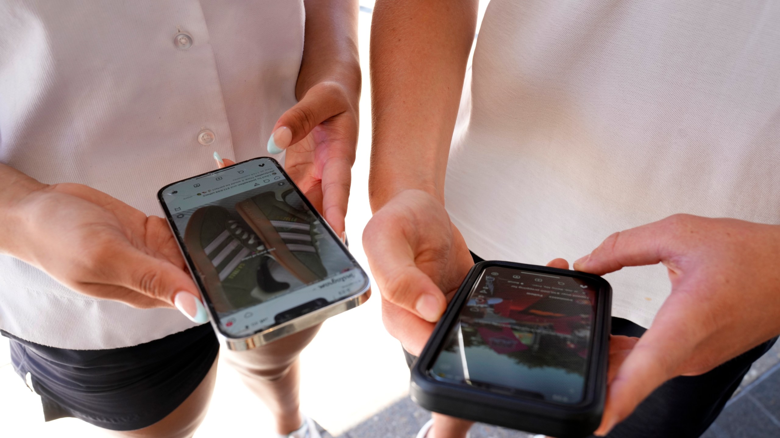 FILE -14-year-old Henry, right, and Angel, 15, use their phones to view social media in Sydney, on Nov. 8, 2024. (AP Photo/Rick Rycroft, File)