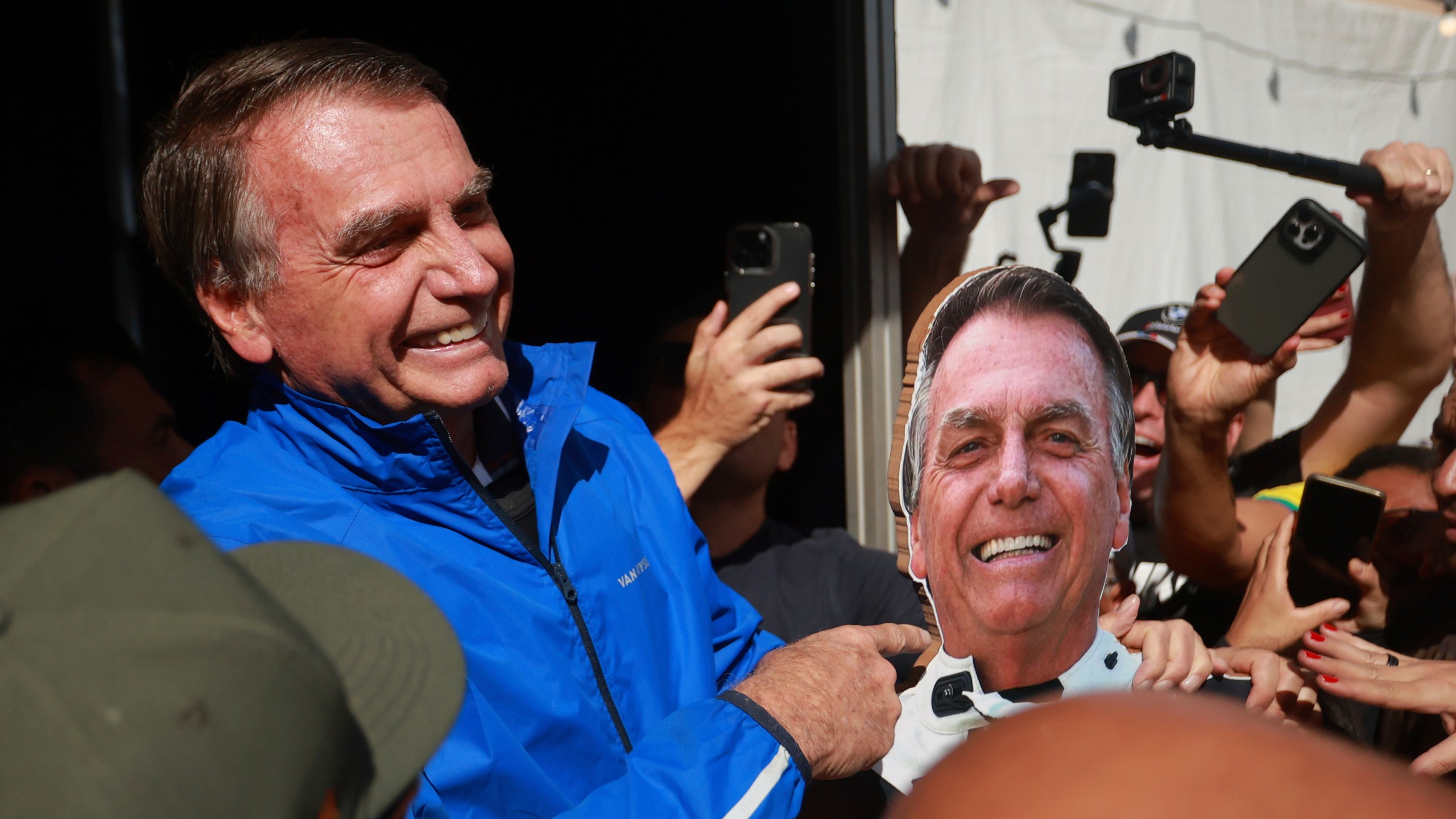 Brazil's former President Jair Bolsonaro points a photo of him during a motorcycle caravan by supporters to protest the Supreme Court trial where he faces charges for alleged involvement in a 2022 coup attempt, in Brasília, Brazil, Tuesday, July 29, 2025. (AP Photo/Luis Nova)
