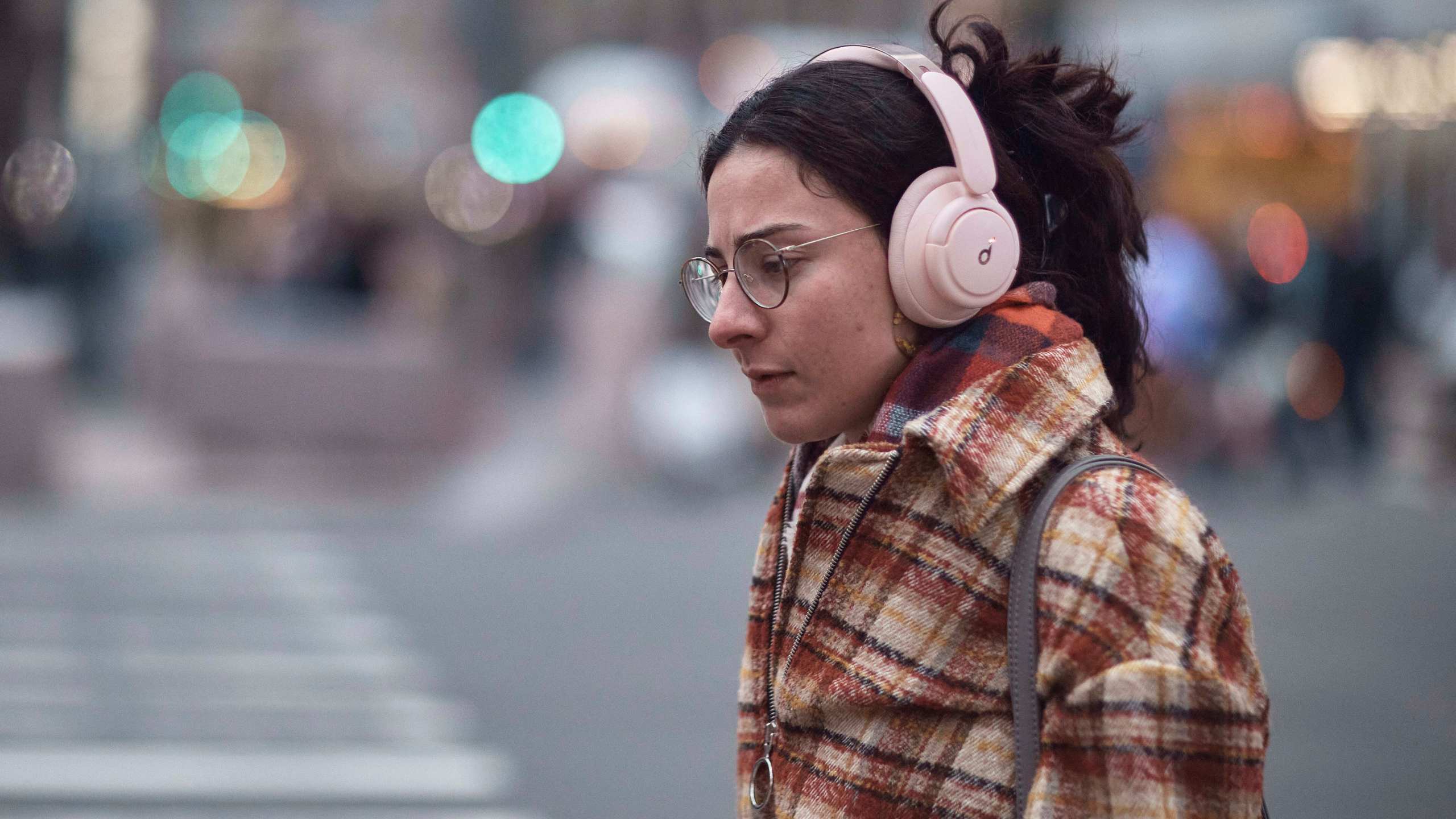 FILE - A woman walks using her headphones on Tuesday, Jan. 17, 2023, in New York. (AP Photo/Andres Kudacki, File)