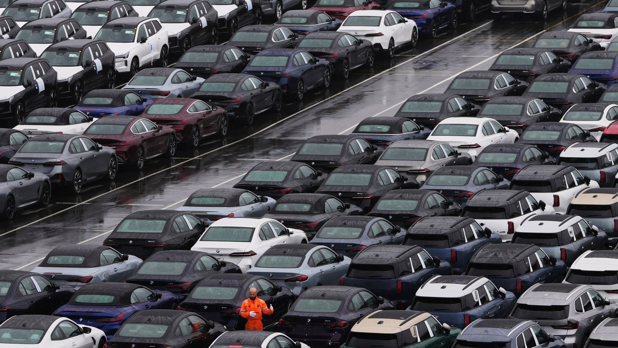 A worker checks on new cars parked in a lot at the International Car Operators terminal in the Port of Zeebrugge, Belgium, Thursday, July 31, 2025. (AP Photo/Virginia Mayo)