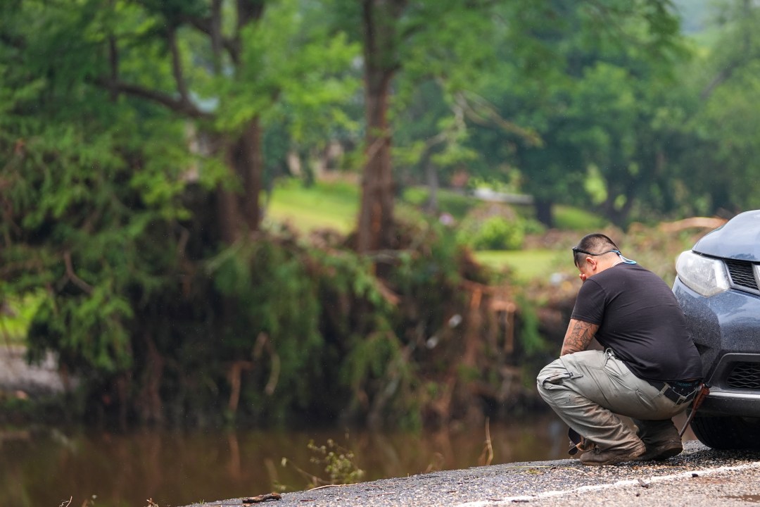Avi Santos, 23, of San Antonio, Texas, reacts while stopping on the road alongside at Camp Mystic along the banks of the Guadalupe River