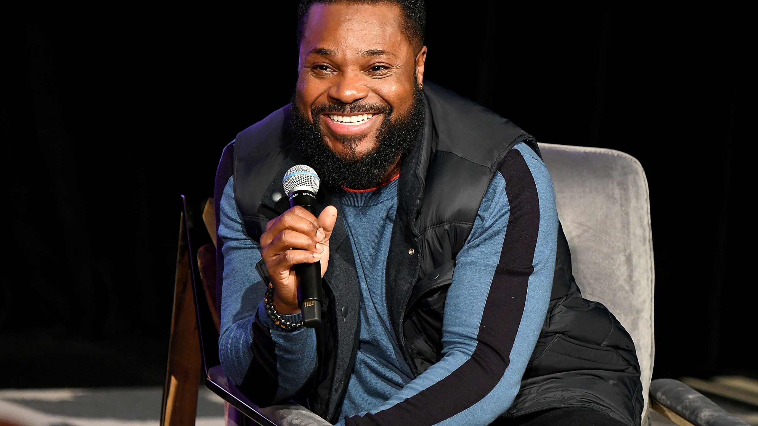 Malcolm-Jamal Warner hokding a microphone