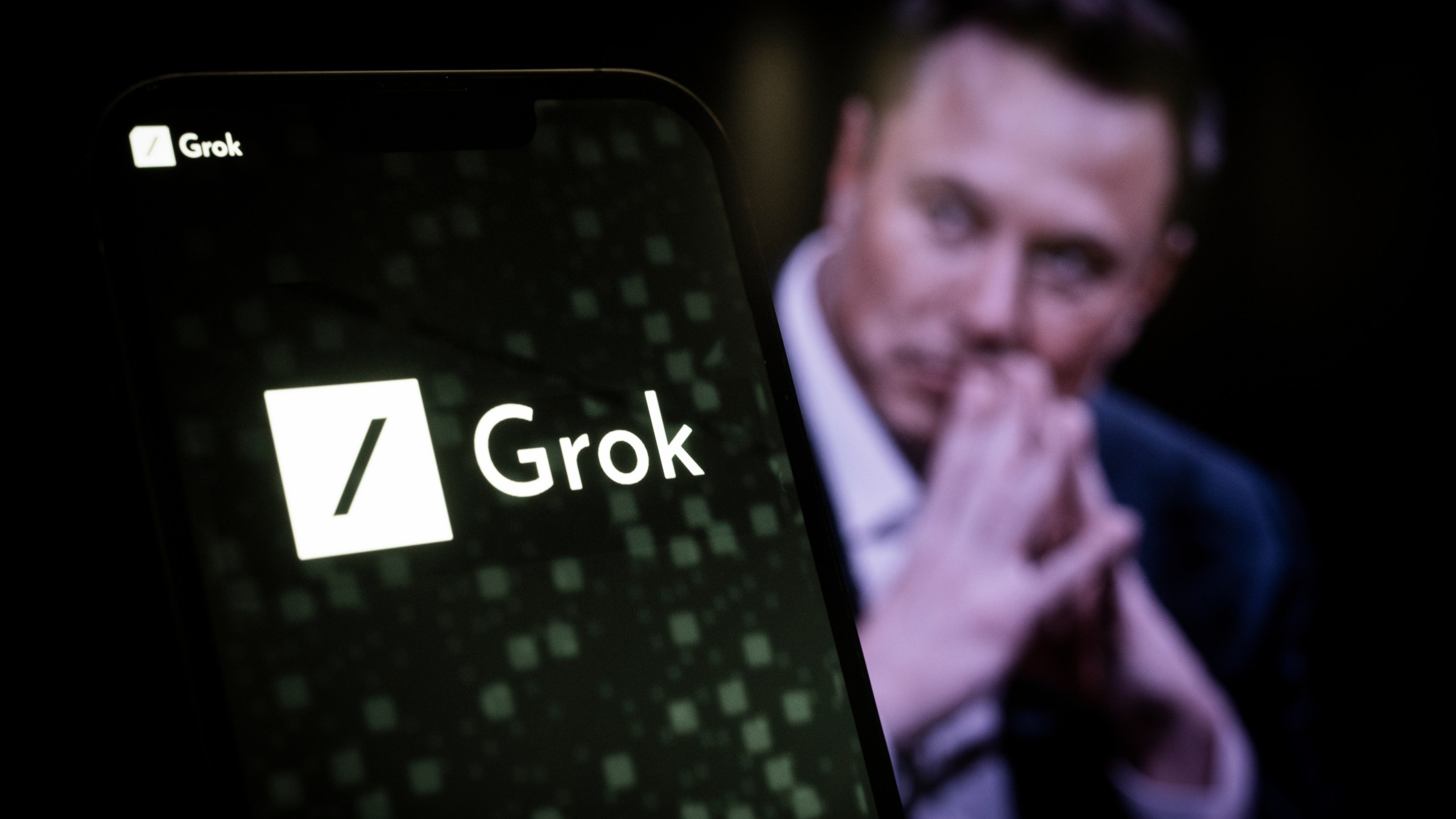 'Grok' logo with Elon Musk in background