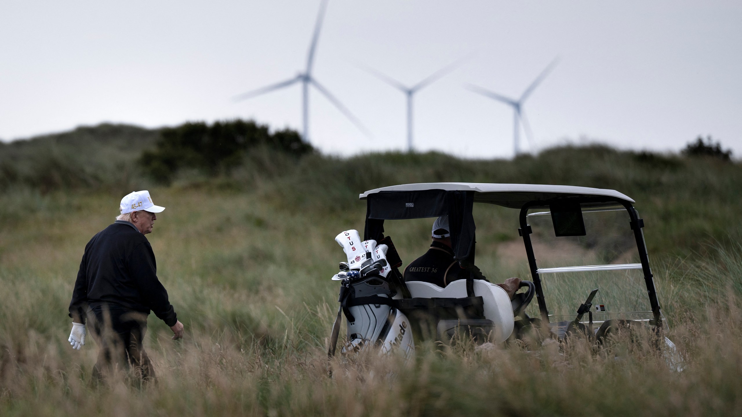 Trump on golf course with wind turbines in background