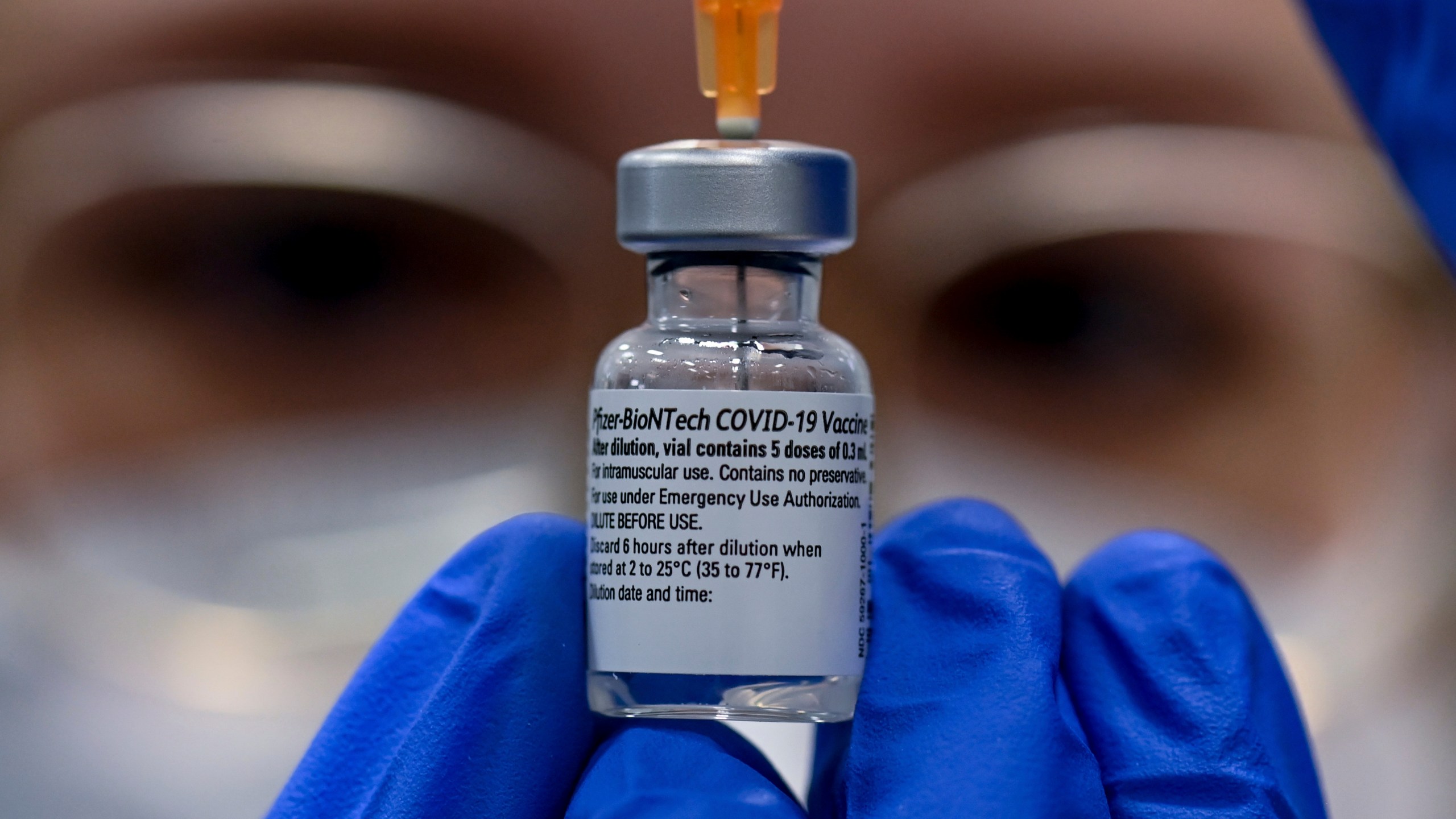 a pharmacist holding a vial of vaccine