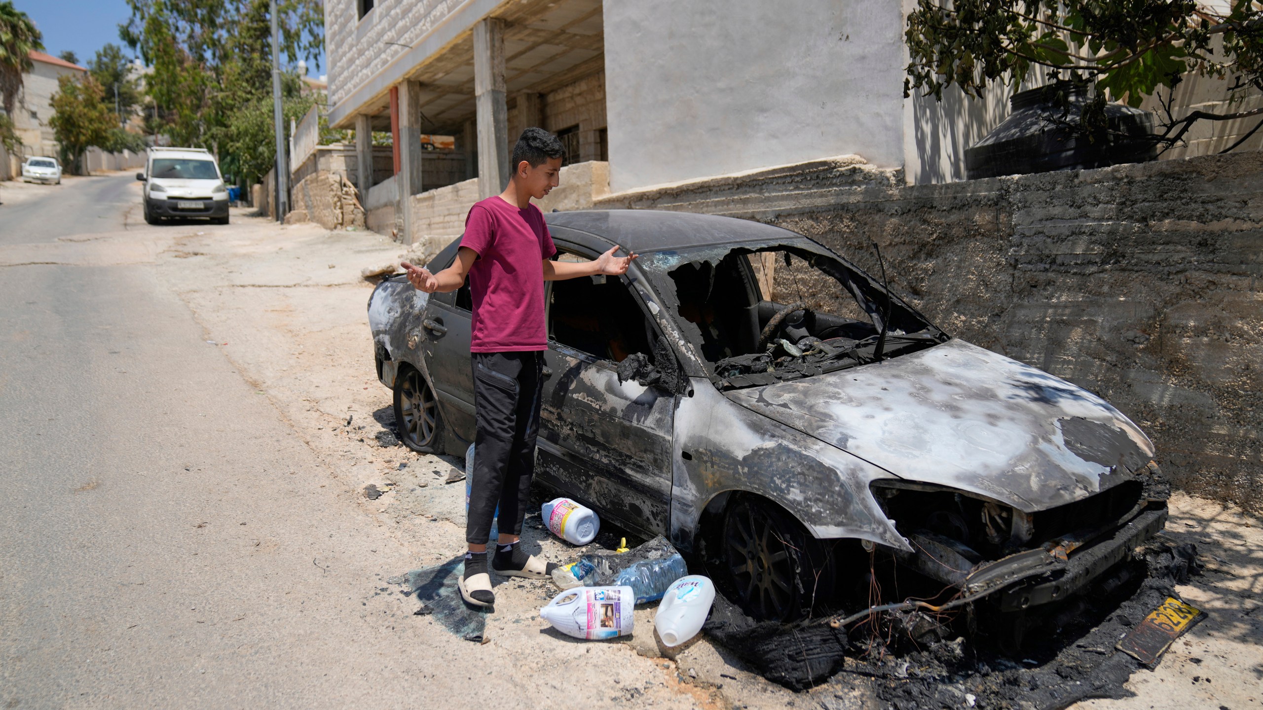 A resident inspects a torched vehicle following a spree of violent rampage by Israeli settlers overnight that left one dead Palestinian American, a burnt house and several torched vehicles in three Palestinian towns, in the West Bank town of Rammun, east of Ramallah Thursday, July 31, 2025. (AP Photo/Nasser Nasser)