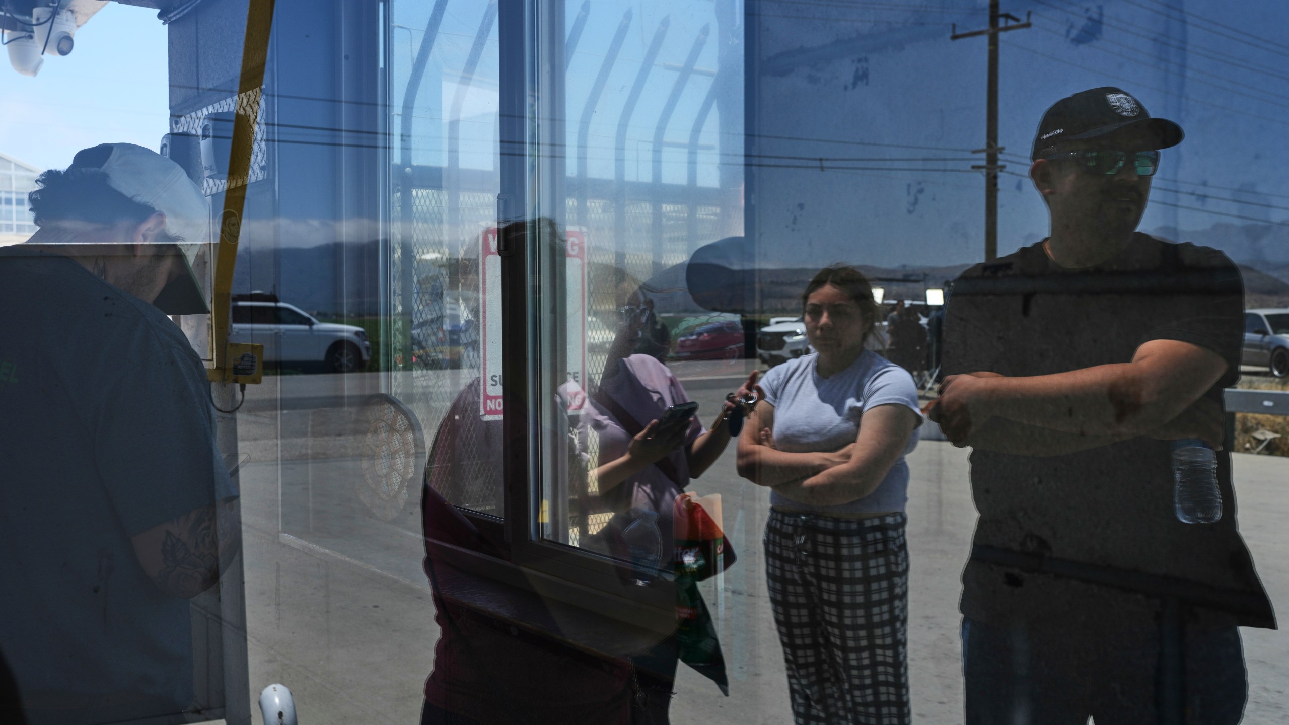 FILE - People wait outside of Glass House Farms, a day after an immigration raid on the facility, Friday, July 11, 2025, in Camarillo, Calif. (AP Photo/Jae C. Hong, File)