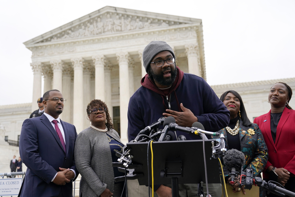 FILE - Evan Milligan, center, plaintiff in Merrill v. Milligan, an Alabama redistricting case, speaks with reporters following oral arguments at the Supreme Court in Washington, Oct. 4, 2022. (AP Photo/Patrick Semansky, File)