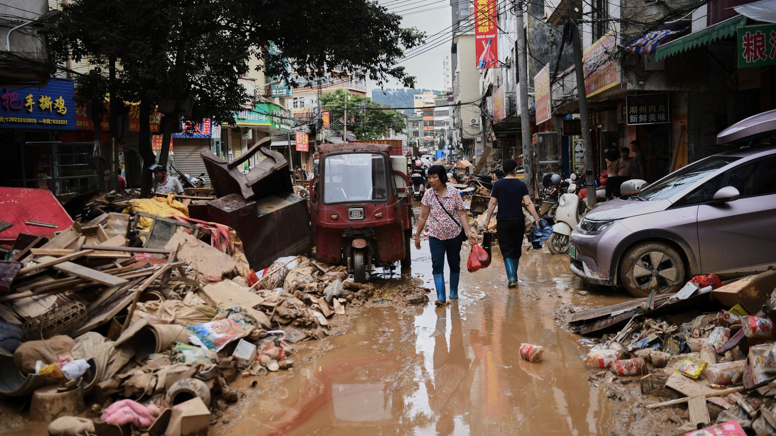 FILE -In this photo released by Xinhua News Agency, residents wade through debris along a flood-hit street after waters from a river overwhelmed towns following days of heavy rain, in Huaiji County, south China's Guangdong Province on June 19, 2025. (Deng Hua/Xinhua via AP, File)