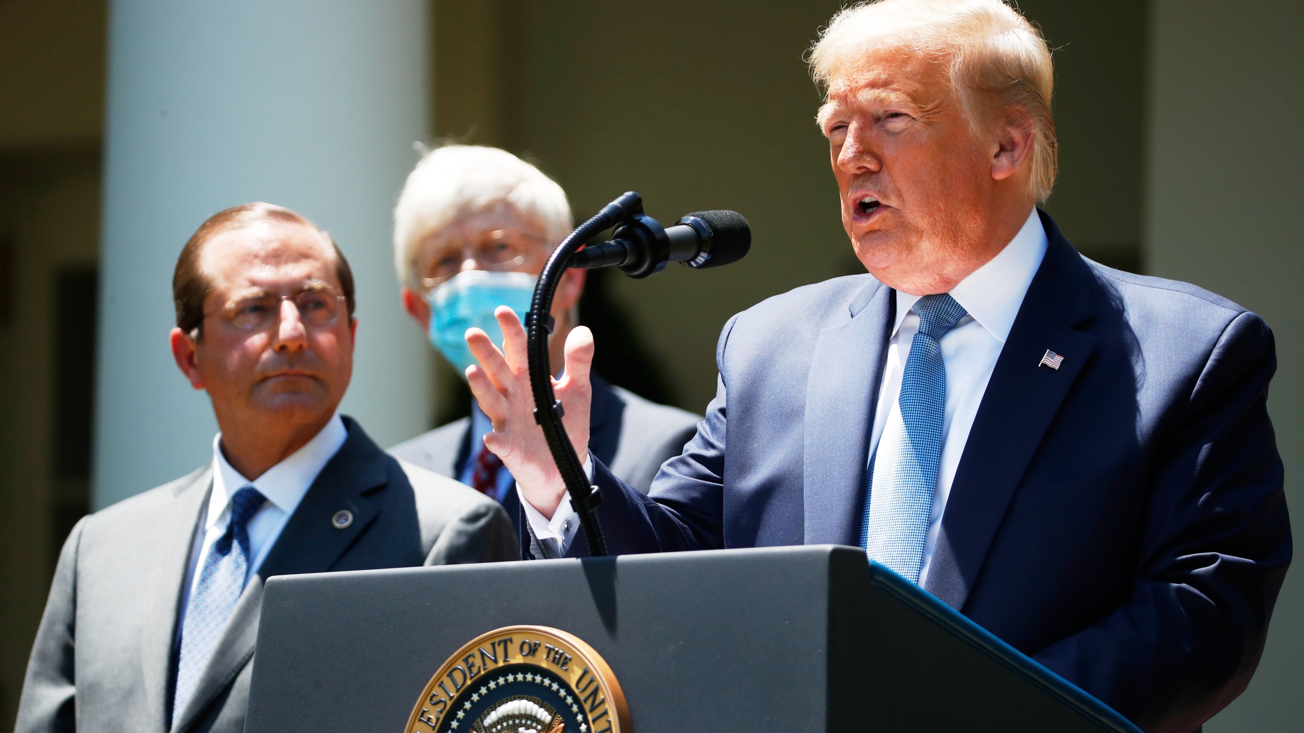 FILE - President Donald Trump speaks about the coronavirus in the Rose Garden of the White House, May 15, 2020, in Washington. Department of Health and Human Services Secretary Alex Azar, left, and Dr. Robert Redfield, director of the Centers for Disease Control and Prevention listen. (AP Photo/Alex Brandon, File)