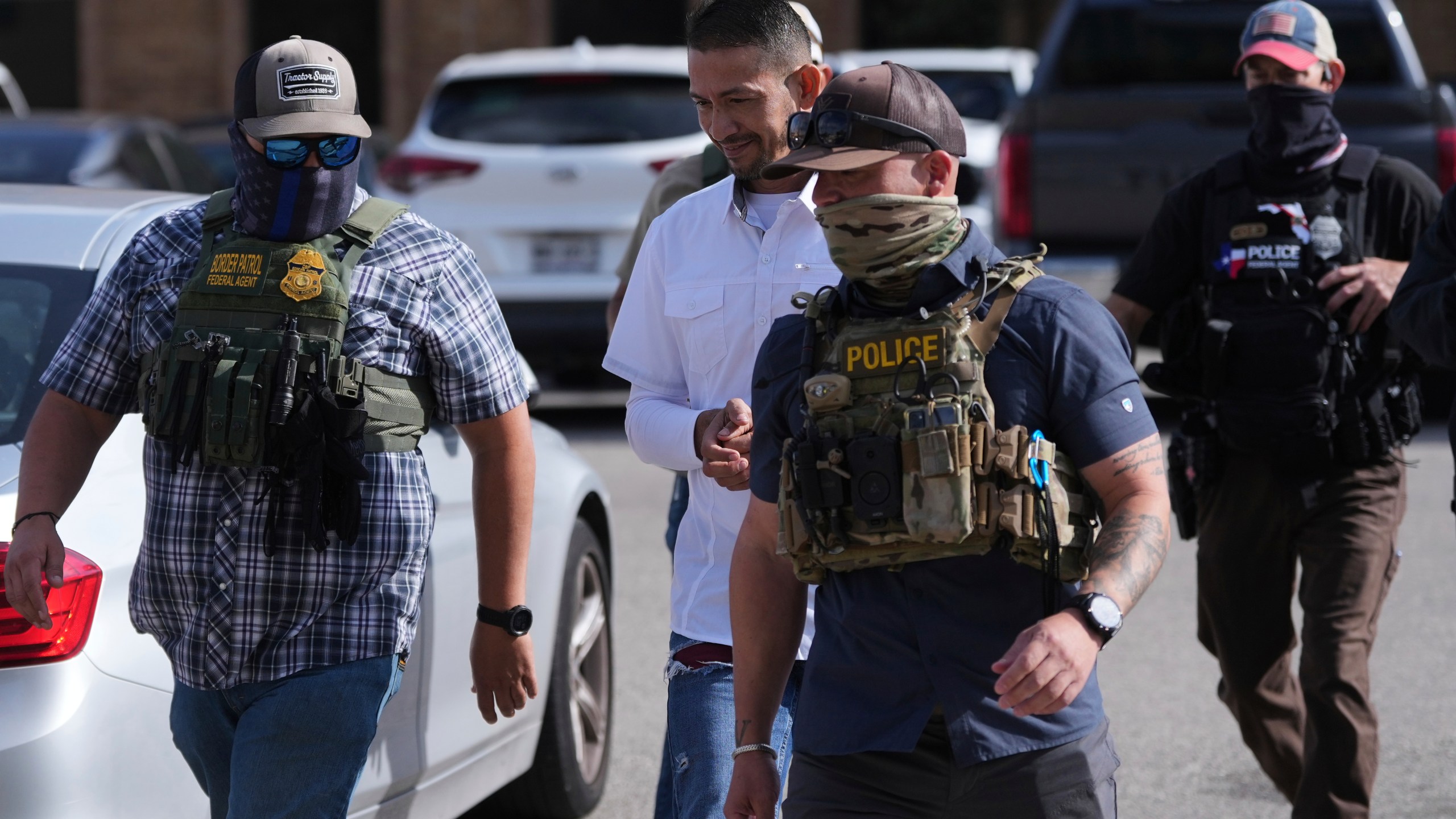 Federal agents escort a man to a transport bus after he was detained following an appearance at immigration court, Tuesday, July 22, 2025, in San Antonio. (AP Photo/Eric Gay)