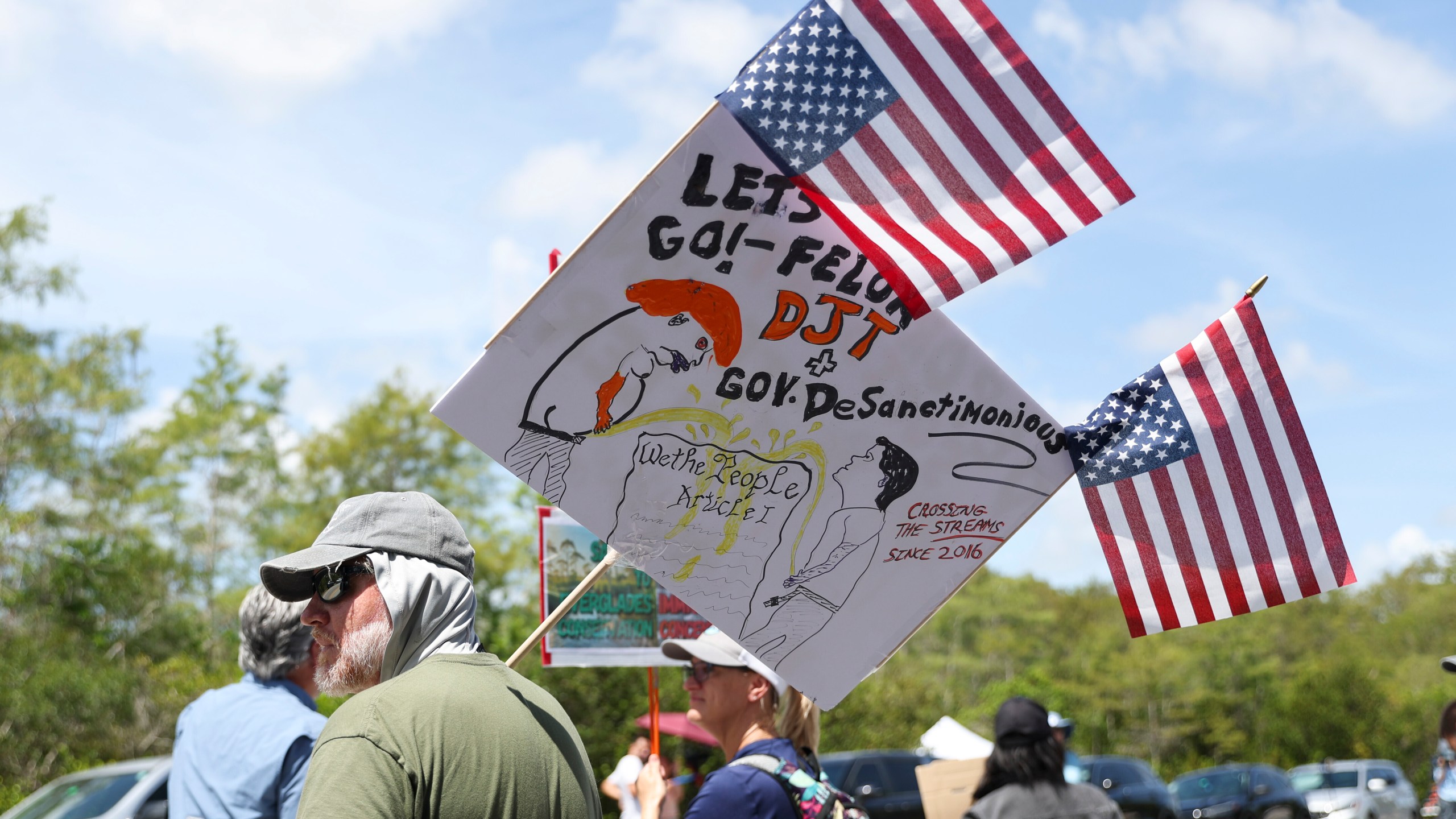 A protester stands outside the migrant detention dubbed "Alligator Alcatraz" at the Dade-Collier Training and Transition Facility, Saturday, July 12, 2025, in Ochopee, Fla. (AP Photo/Alexandra Rodriguez)