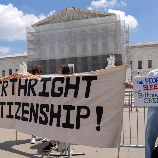 protesters hold up a banner in front of the Supreme Court building reading HANDS OFF BIRTHRIGHT CITIZENSHIP