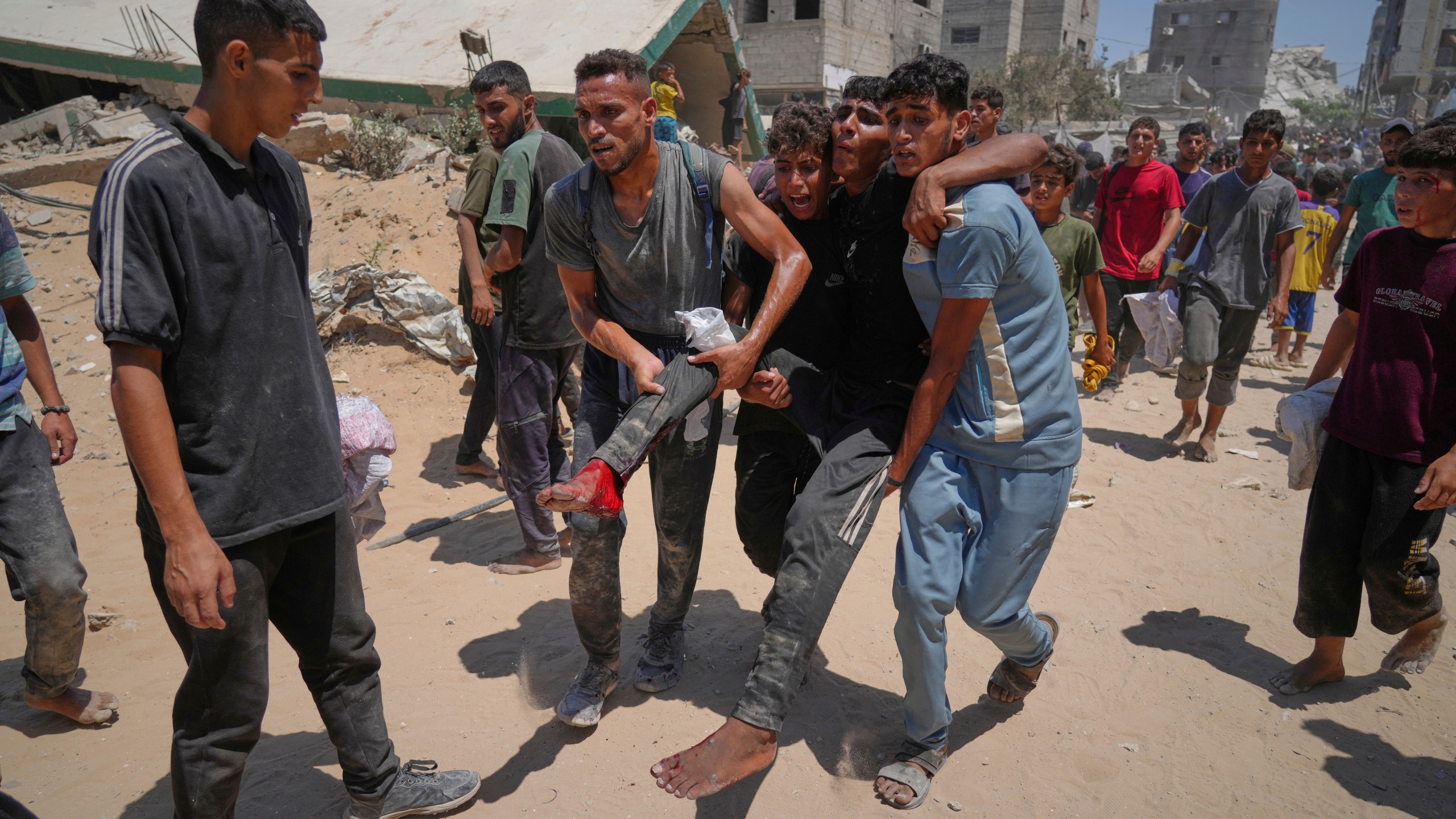 Palestinians carry a wounded man who was injured while rushing to collect humanitarian aid airdropped by parachute into Gaza City, in the northern Gaza Strip, Thursday, Aug. 7, 2025. (AP Photo/Jehad Alshrafi)
