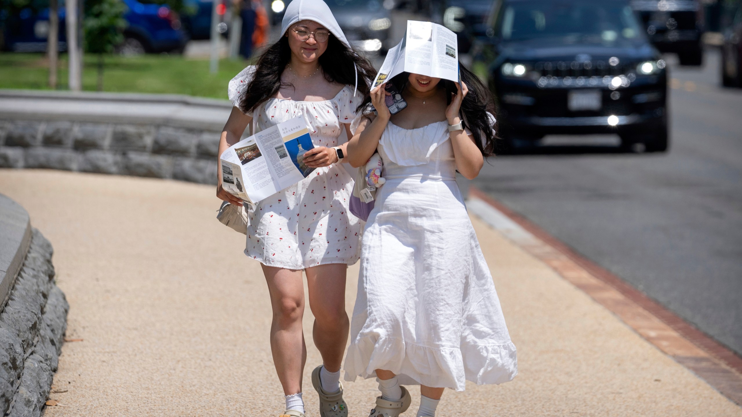 FILE - Visitors use brochures to shield themselves from the sun as they walk near the U.S. Capitol on an unseasonably hot day, June 24, 2025, in Washington. (AP Photo/Mark Schiefelbein, File)