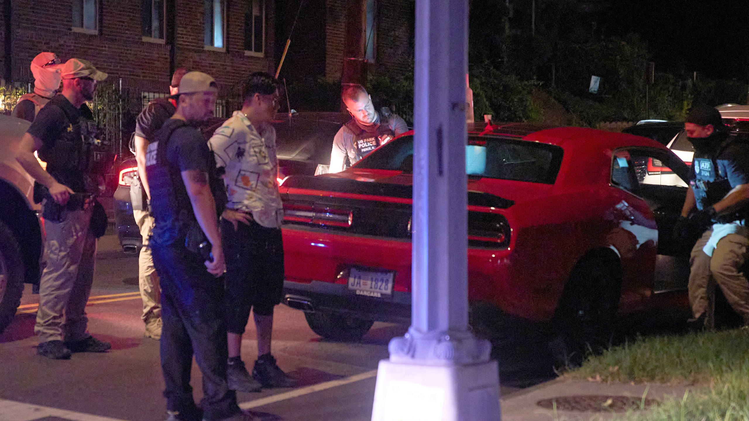 Agents from various agencies including Bureau of Alcohol, Tobacco, Firearms and Explosives, Park Police, and FBI, question a couple who had been parked in a car with Washington D.C. plates outside of a legal parking spot while eating McDonald's takeout, Tuesday, Aug. 12, 2025, in northwest Washington near Kennedy St. NW. The couple were released after a search of the car. (AP Photo/Jacquelyn Martin)