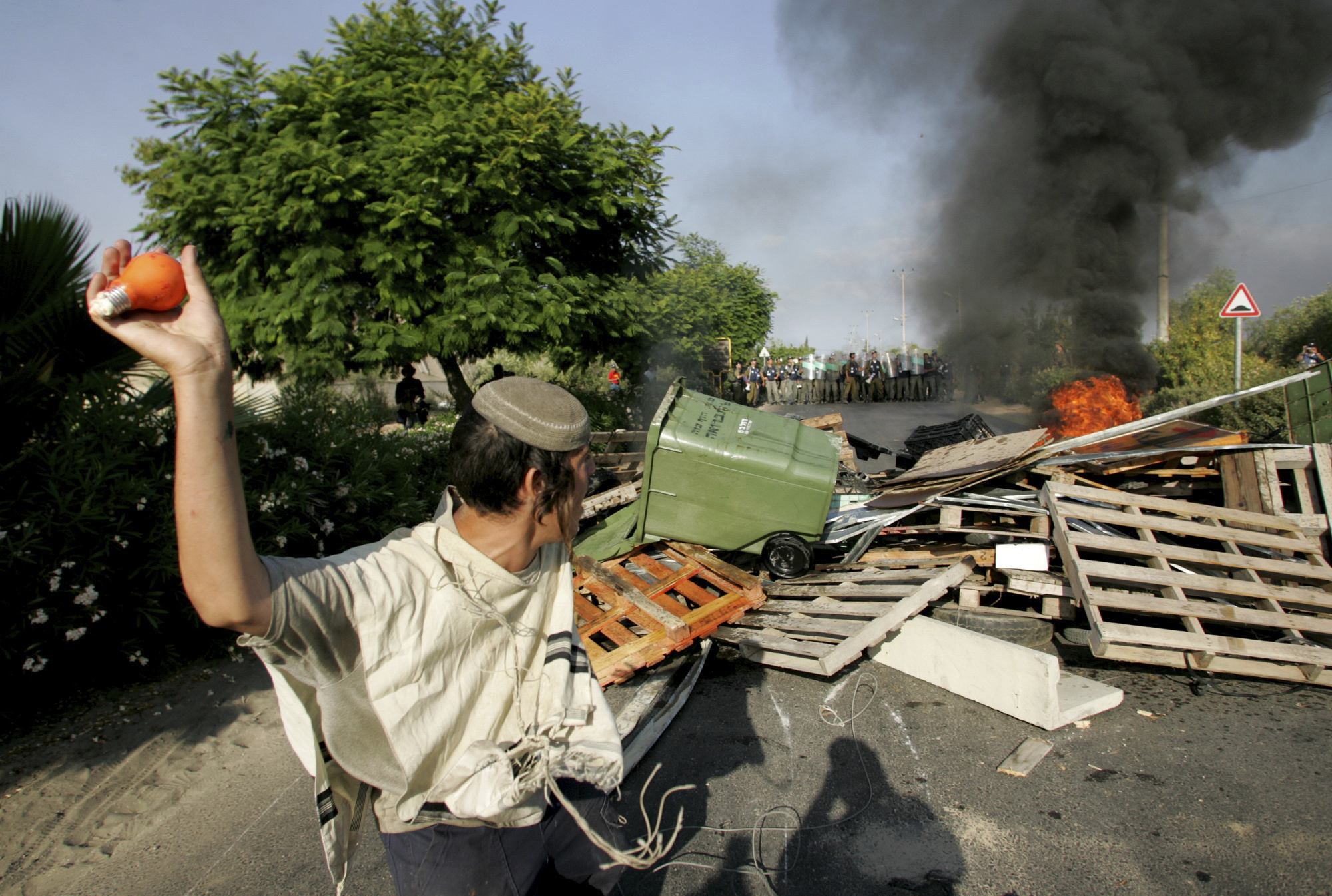 FILE - A Jewish settler prepares to throw a light bulb filled with orange paint at Israeli police, as they arrive in the Jewish settlement of Gadid, Aug. 19, 2005. (AP Photo/David Guttenfelder, File)