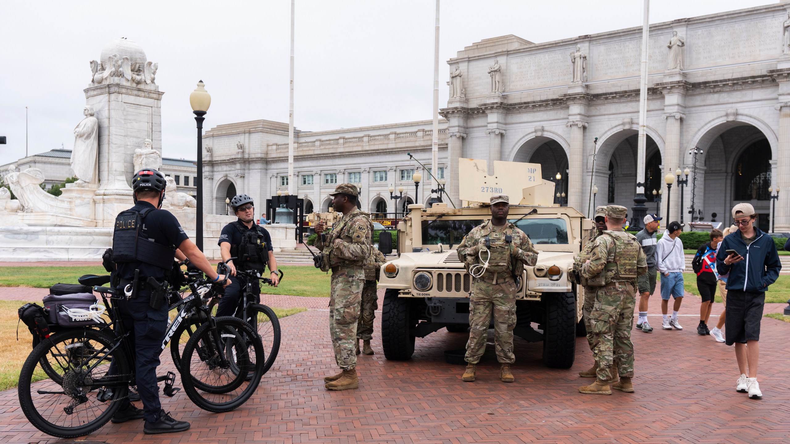 U.S. Capitol Police officers on bike patrol talk to District of Columbia Army National Guardsmen standing next to their Humvee military utility vehicle, outside Union Station near the U.S. Capitol in Washington, Tuesday, Aug. 19, 2025. (AP Photo/Manuel Balce Ceneta)