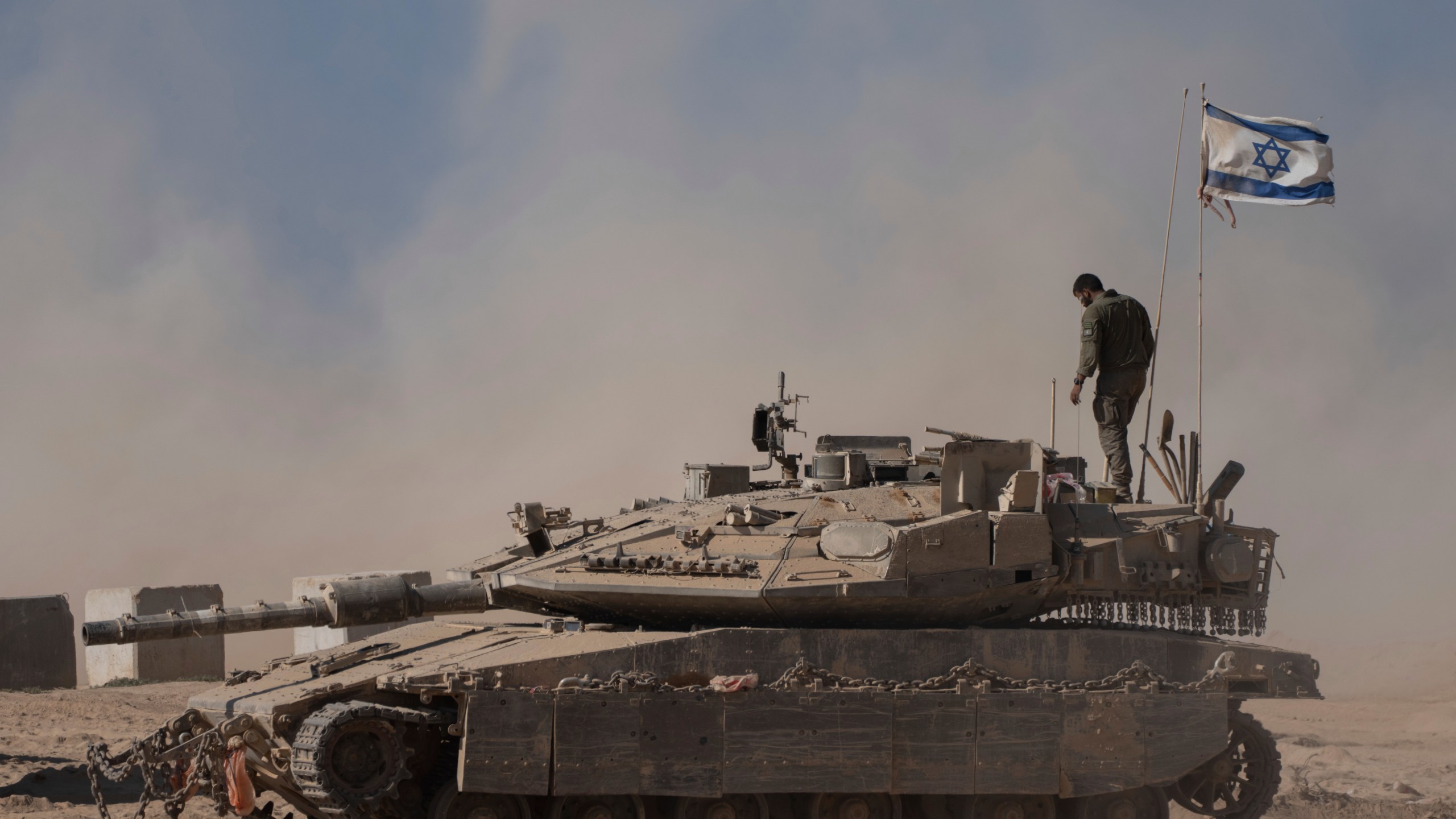 An Israeli soldier stands on the top of a tank parked on an area near the Israeli-Gaza border, as seen from southern Israel, Wednesday, Aug. 20, 2025. (AP Photo/Maya Levin)