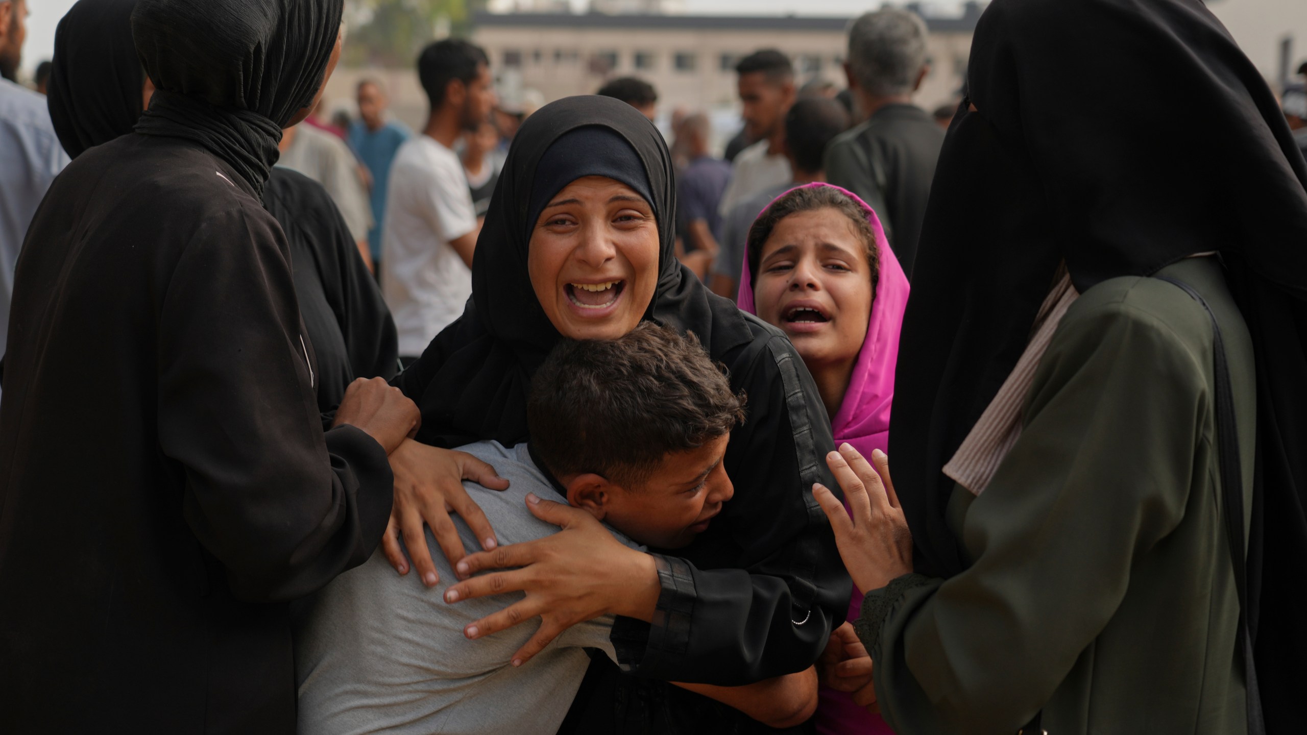 The mother of Mohammed Al-Sukni, center, who was killed while trying to reach aid trucks, is comforted by relatives outside Shifa Hospital, before his funeral in Gaza City, Thursday, Aug. 21, 2025. (AP Photo/Jehad Alshrafi)