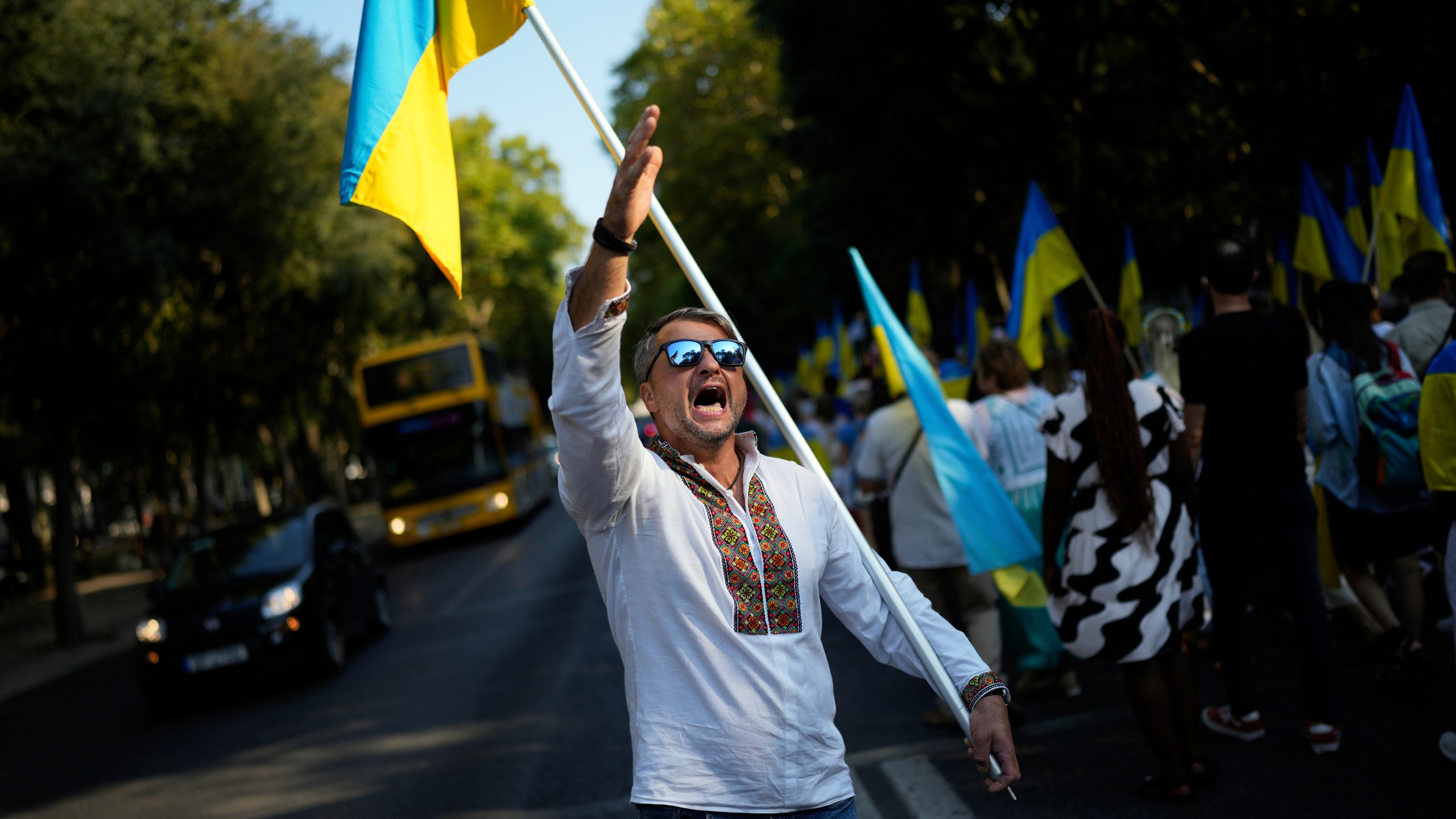 A Ukrainian man shouts during a protest while holding a Ukraine flag
