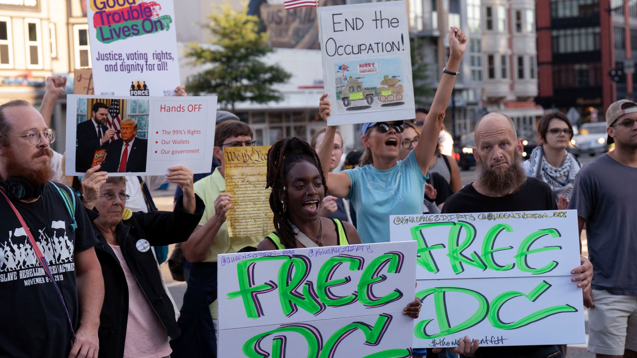 people protest holding signs reading FREE DC and END THE OCCUPATION and GOOD TROUBLE LIVES ON