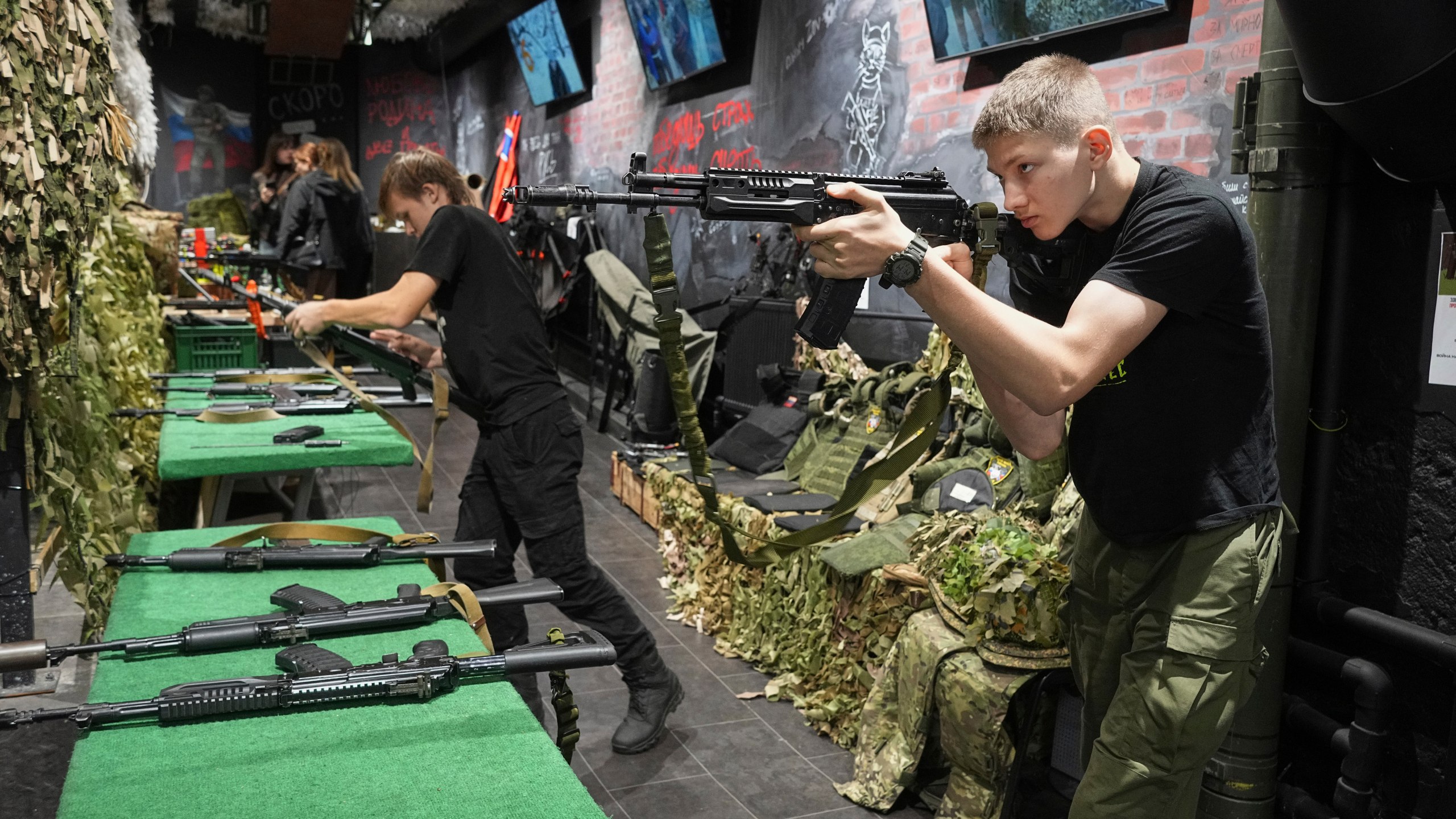 Young men practice with training Kalashnikov assault rifles at a museum of Russian Special Military Operations in Ukraine in St. Petersburg, Russia, Tuesday, Aug. 26, 2025. (AP Photo/Dmitri Lovetsky)