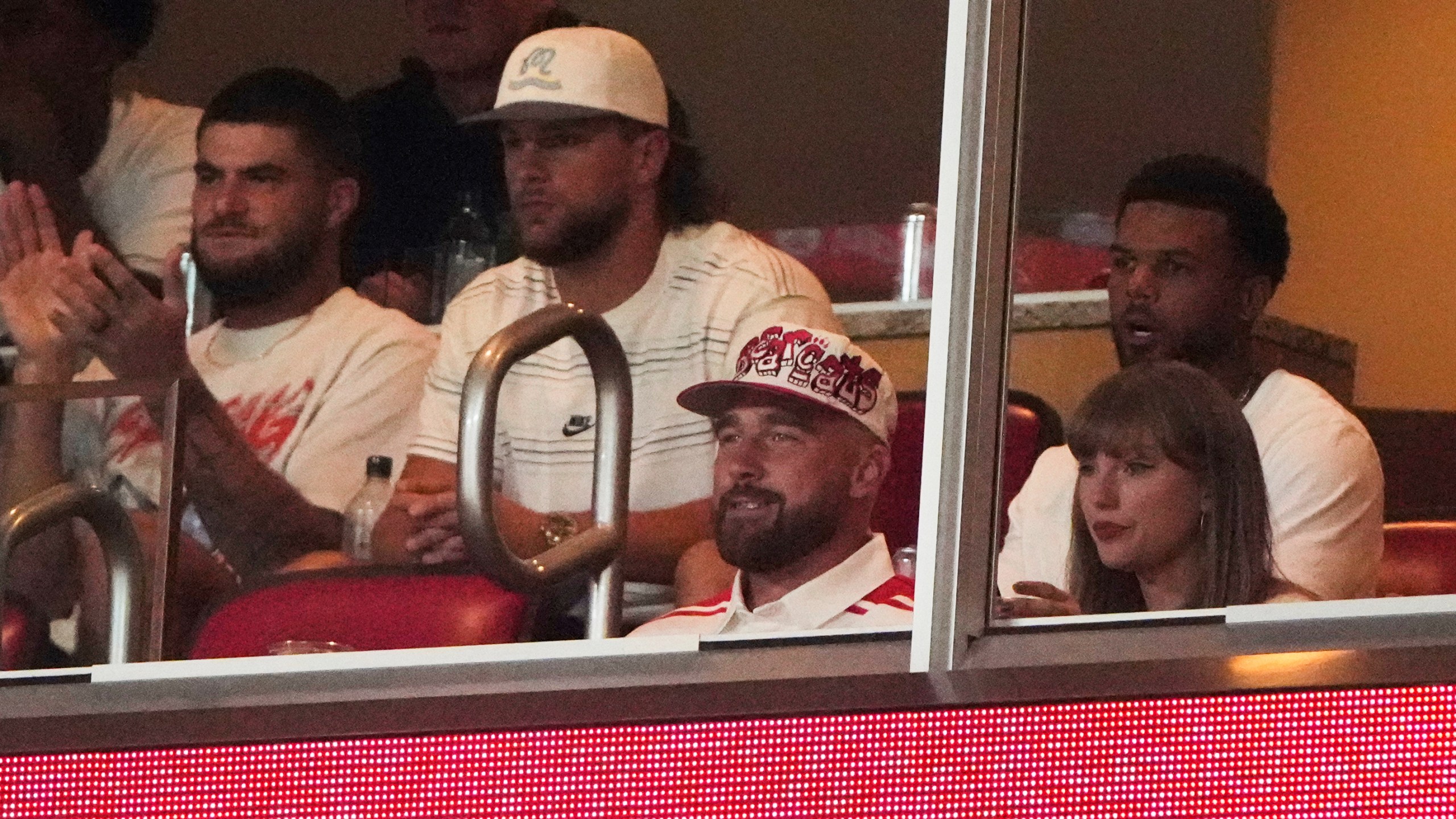 Taylor Swift, front right, sits with fiance Travis Kelce, second from front left, as they watch the first half of an NCAA college football game between Cincinnati and Nebraska, Thursday, Aug. 28, 2025, at Arrowhead Stadium in Kansas City, Mo. (AP Photo/Charlie Riedel)