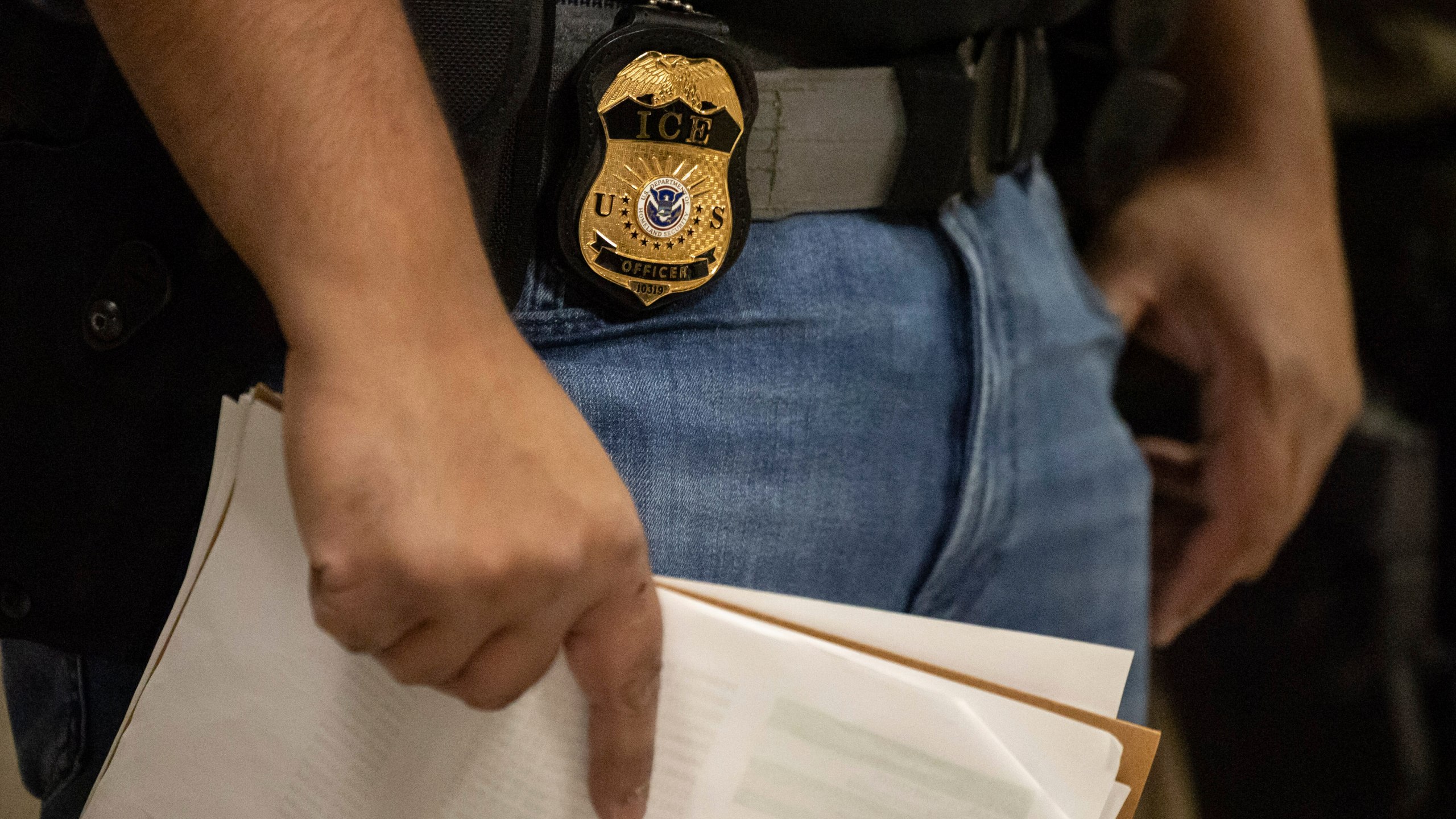 FILE - A federal agent wears a badge of Immigration and Customs Enforcement while standing outside an immigration courtroom at the Jacob K. Javits Federal Building in New York, Tuesday, June 10, 2025. (AP Photo/Yuki Iwamura, File)
